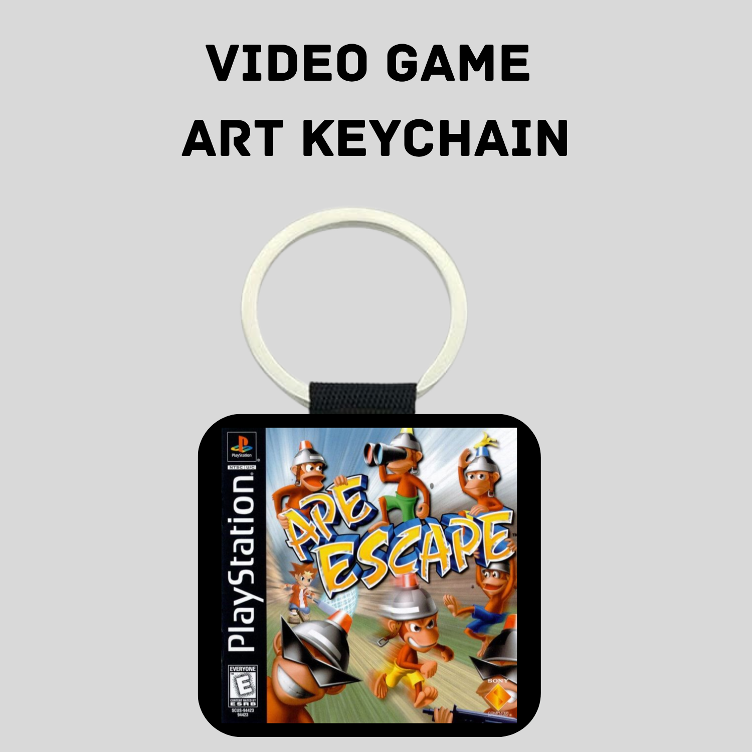 A PlayStation-themed keychain featuring the 'Ape Escape' video game cover art, suspended from a silver split ring against a light gray background with the text 'VIDEO GAME ART KEYCHAIN' above it.