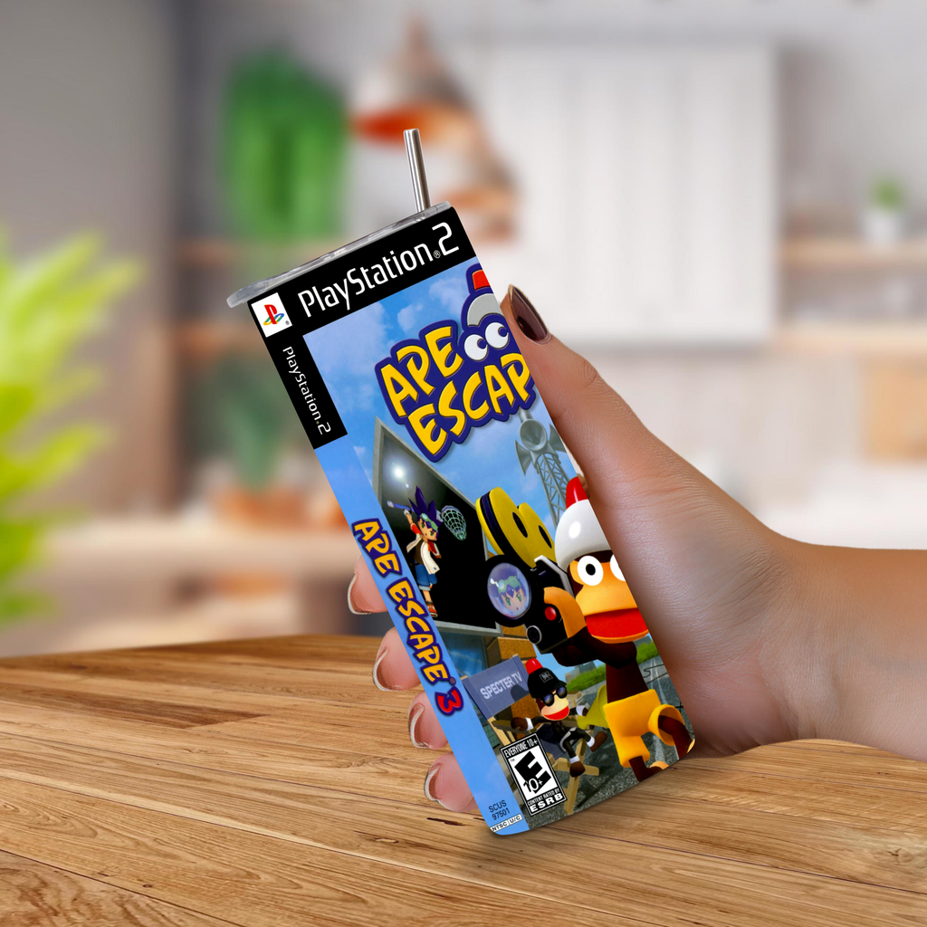 A hand holding a 20oz tumbler designed to look like a PlayStation 2 game case for the game Ape Escape 3, set against a blurred indoor background.