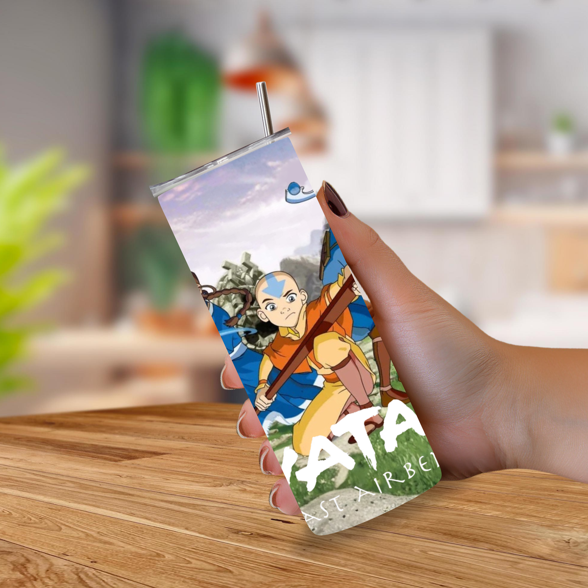 A hand holding a 20oz tumbler with a metal straw, featuring an illustrated print of Aang from Avatar: The Last Airbender.