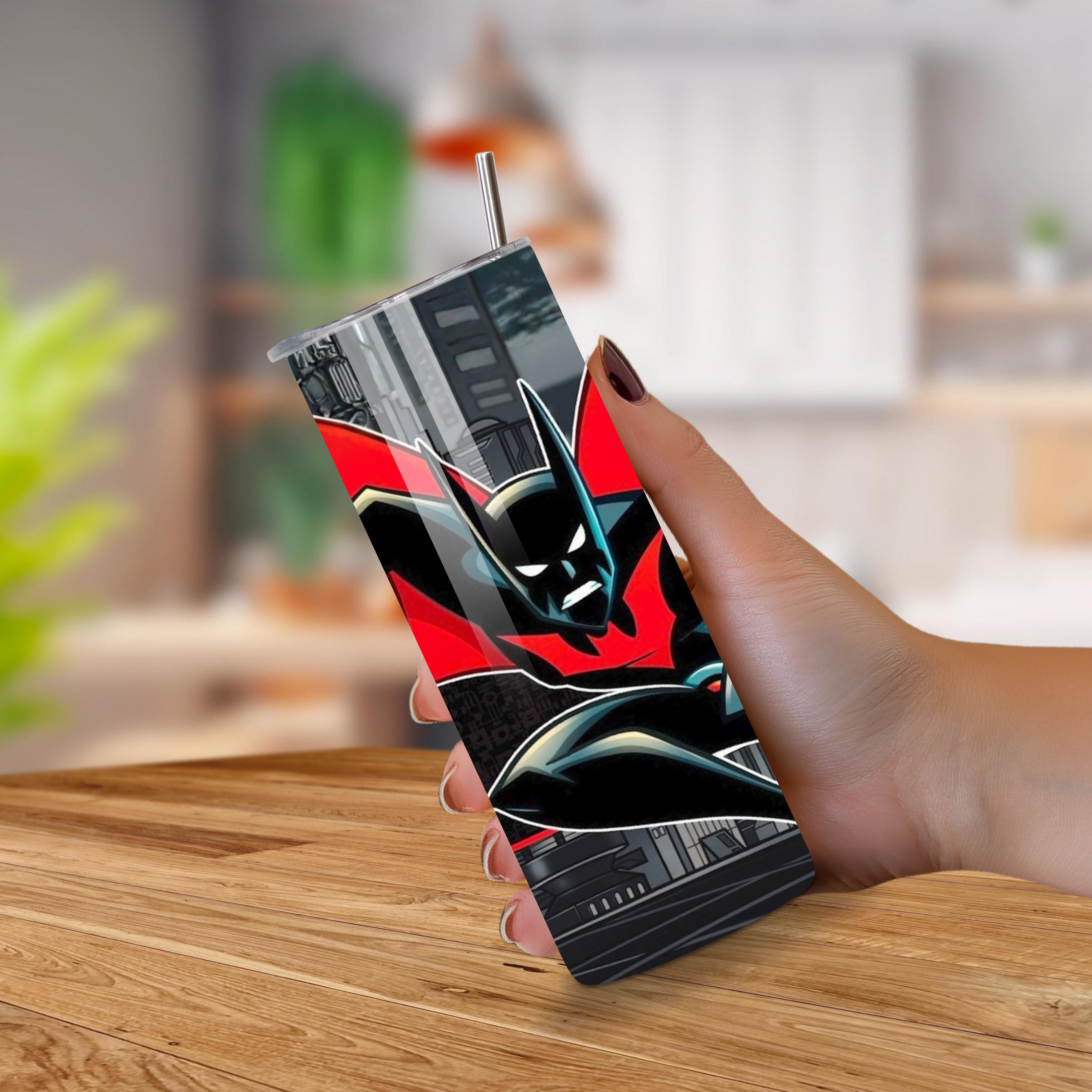 Person holding a tumbler with a Batman Beyond-themed on a wooden surface