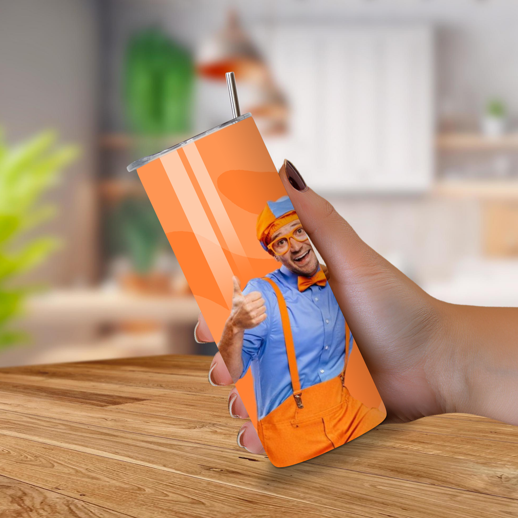 Person holding a custom orange Blippi tumbler with a wood background.