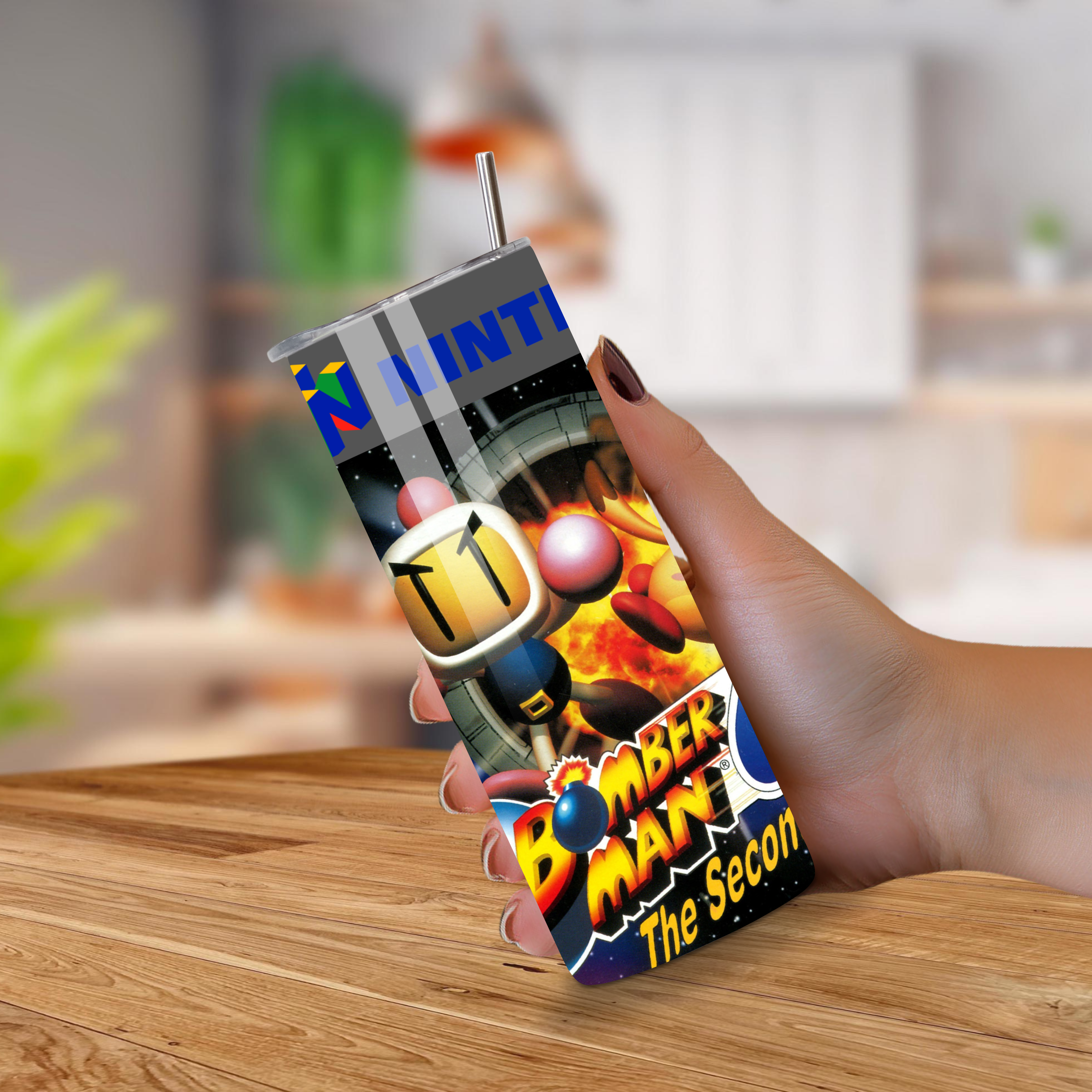 Tumbler with 'Bomber man The Second Attack' design held by a hand on a wooden surface.