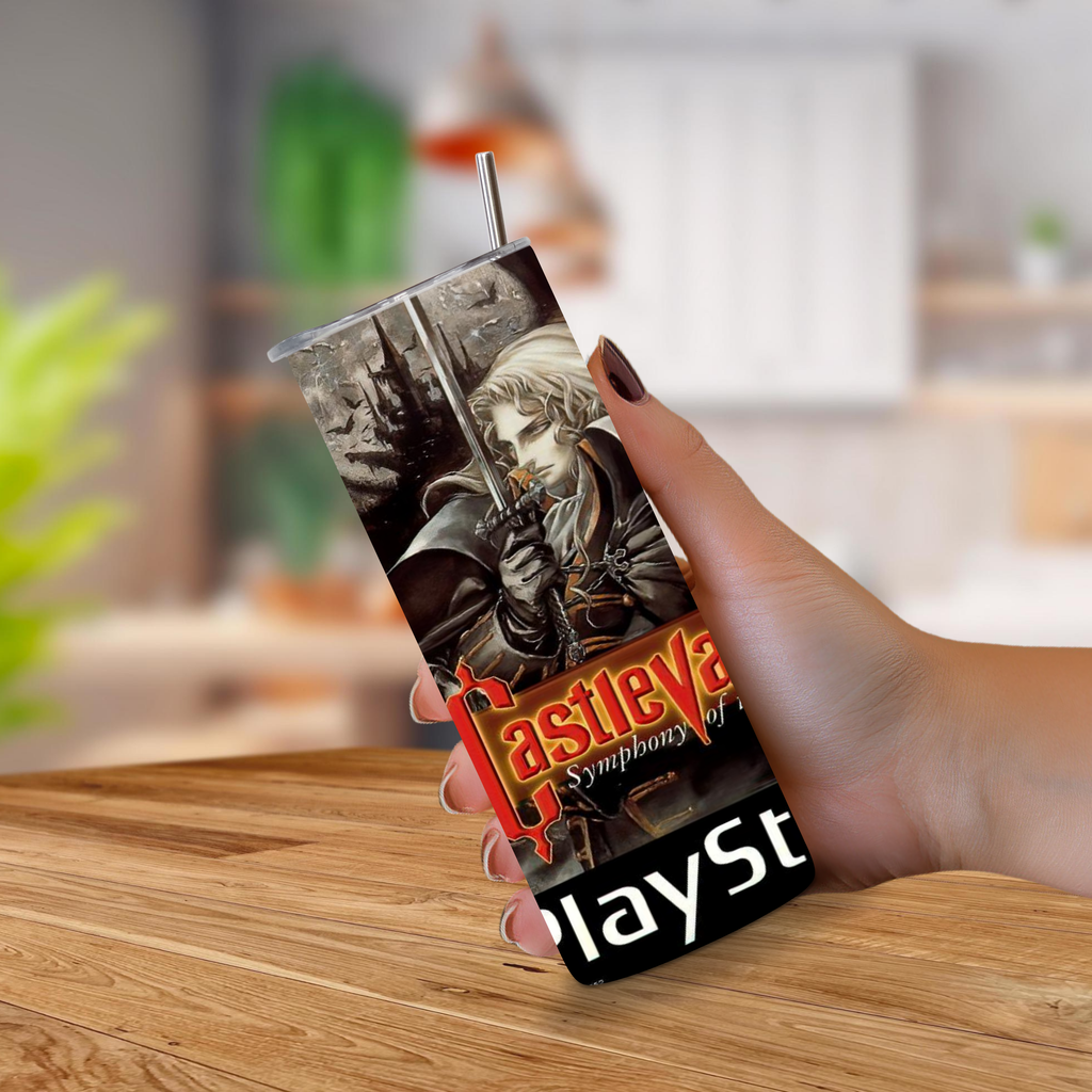 A view of a hand holding a 20oz tumbler with PS1 Castlevania "Symphony of the night" graphics with a blurred and table background. 