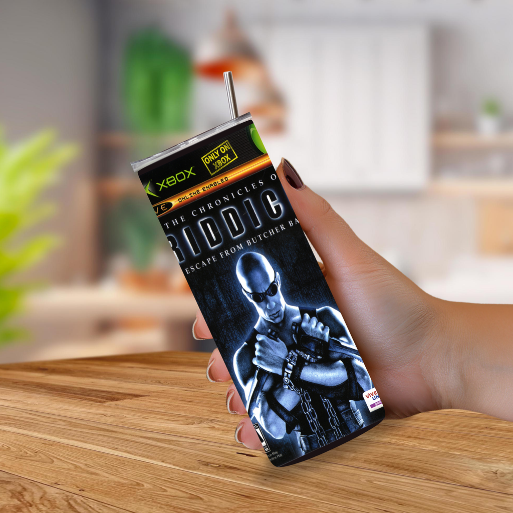 A hand holding a custom Xbox-branded tumbler cup featuring a graphic of the character Riddik from The Chronicles of Riddik, set against a blurred kitchen background.
