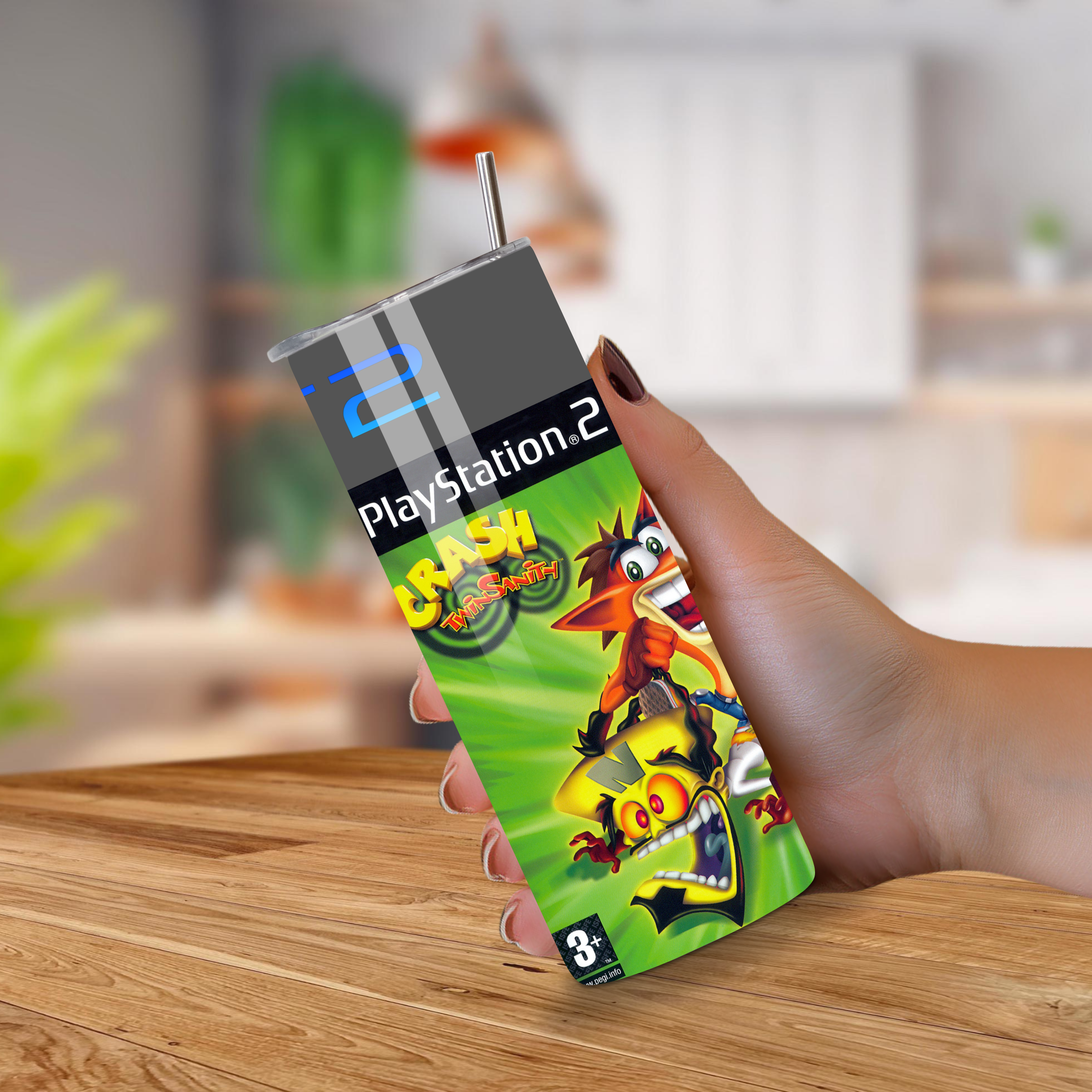 PlayStation 2 20oz Tumbler with 'Crash Twin Sanity' design held by a hand on a wooden surface.