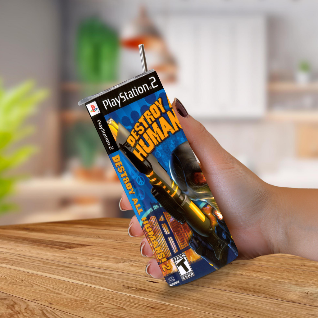A hand holding a PlayStation 2 'Destroy All Human 2' stainless steel tumbler, set against a blurred kitchen background.