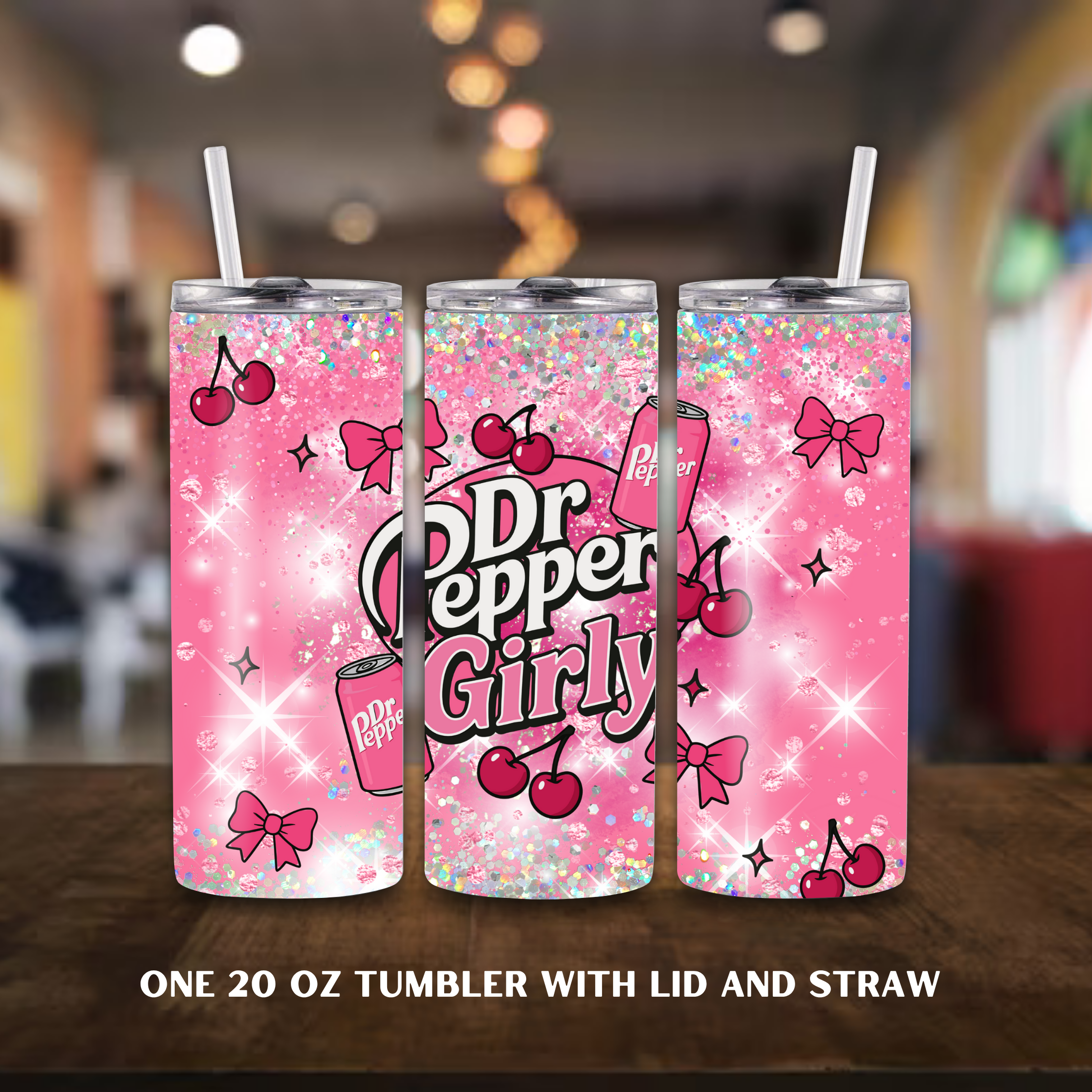 Three pink Dr Pepper tumbler with lid and straw on a wooden surface with a blurred indoor background.