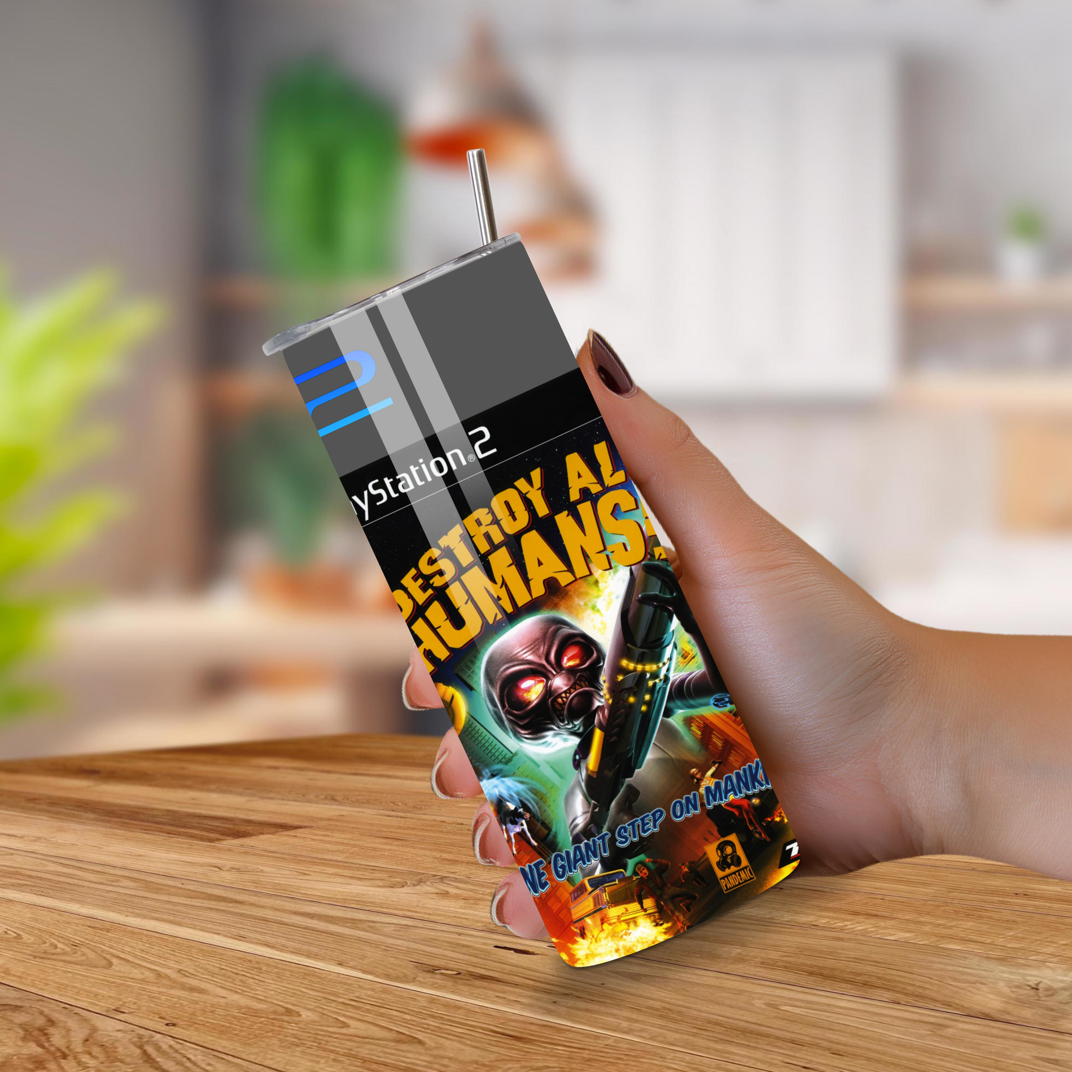 Person holding a 20oz tumbler with Destroy All Humans design on a wooden surface