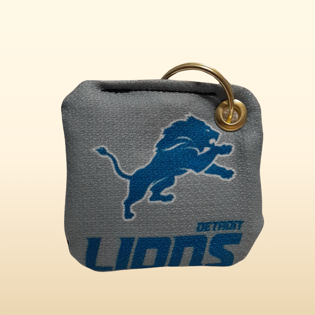 Gray keychain with Detroit Lions logo on a beige background