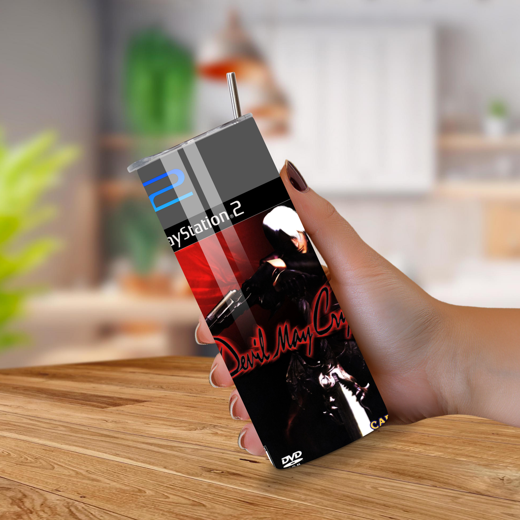 Hand holding a PlayStation 2 tumbler with 'Devil May Cry' design on a wooden surface.