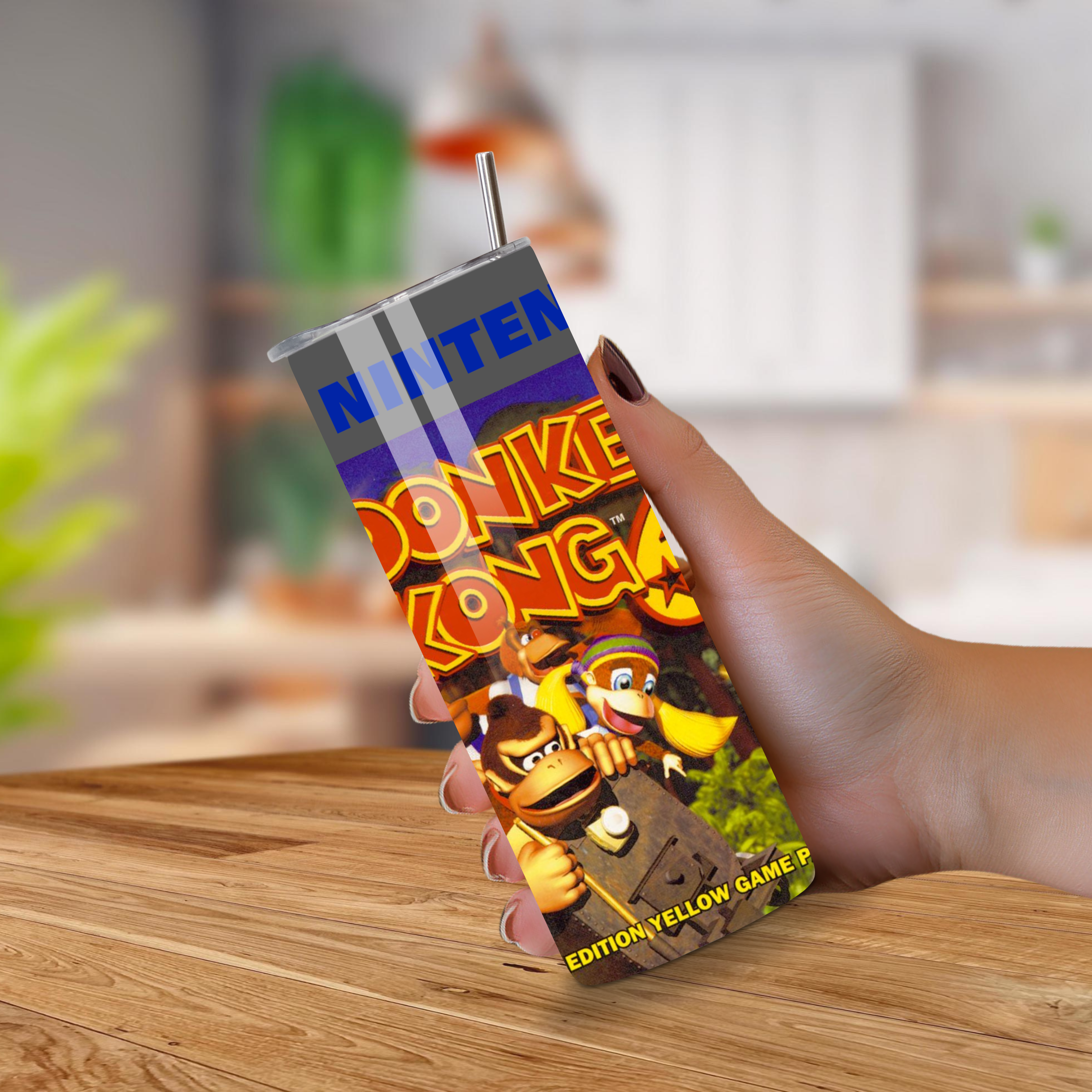 Tumbler drinkware with Donkey Kong design held by a hand on a wooden surface