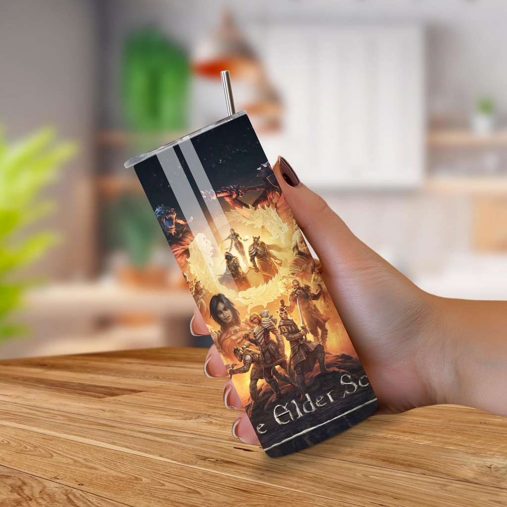 Tumbler with 'The Elder Scrolls' design held by a hand on a wooden surface.