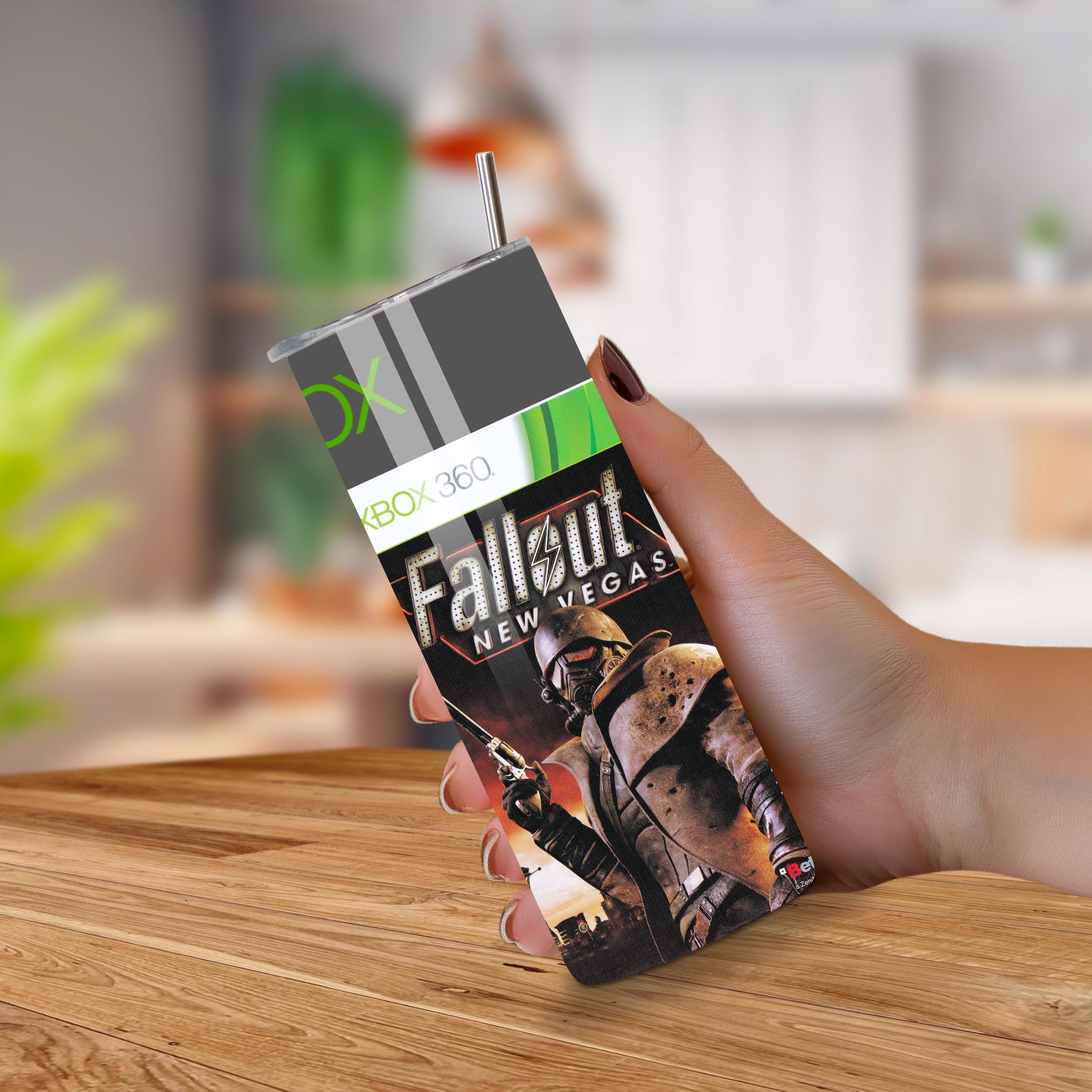 Tumbler with 'Fallout New Vegas' design held by a hand on a wooden surface.