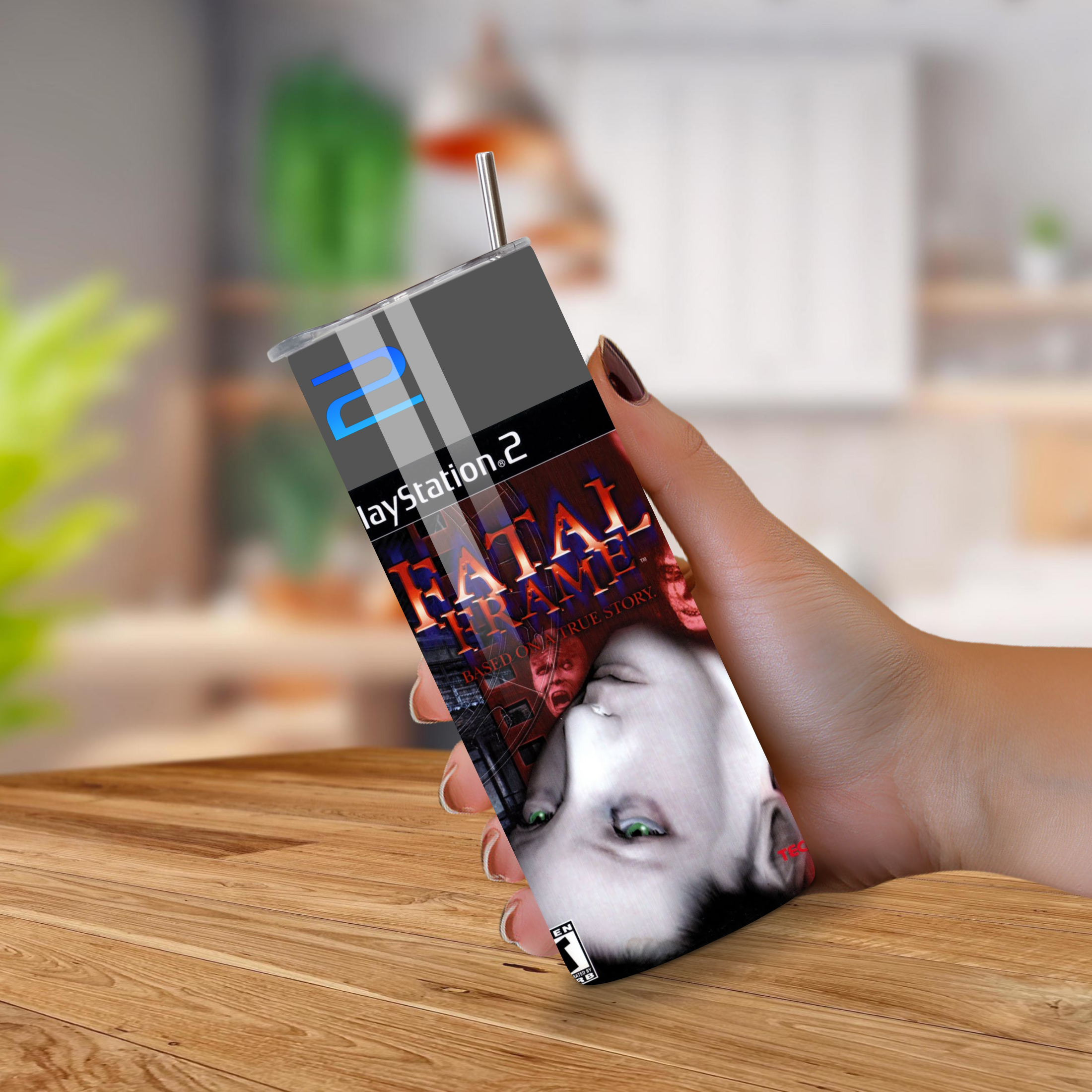 20oz Tumbler with 'Fatal Frame' design held by a hand on a wooden surface