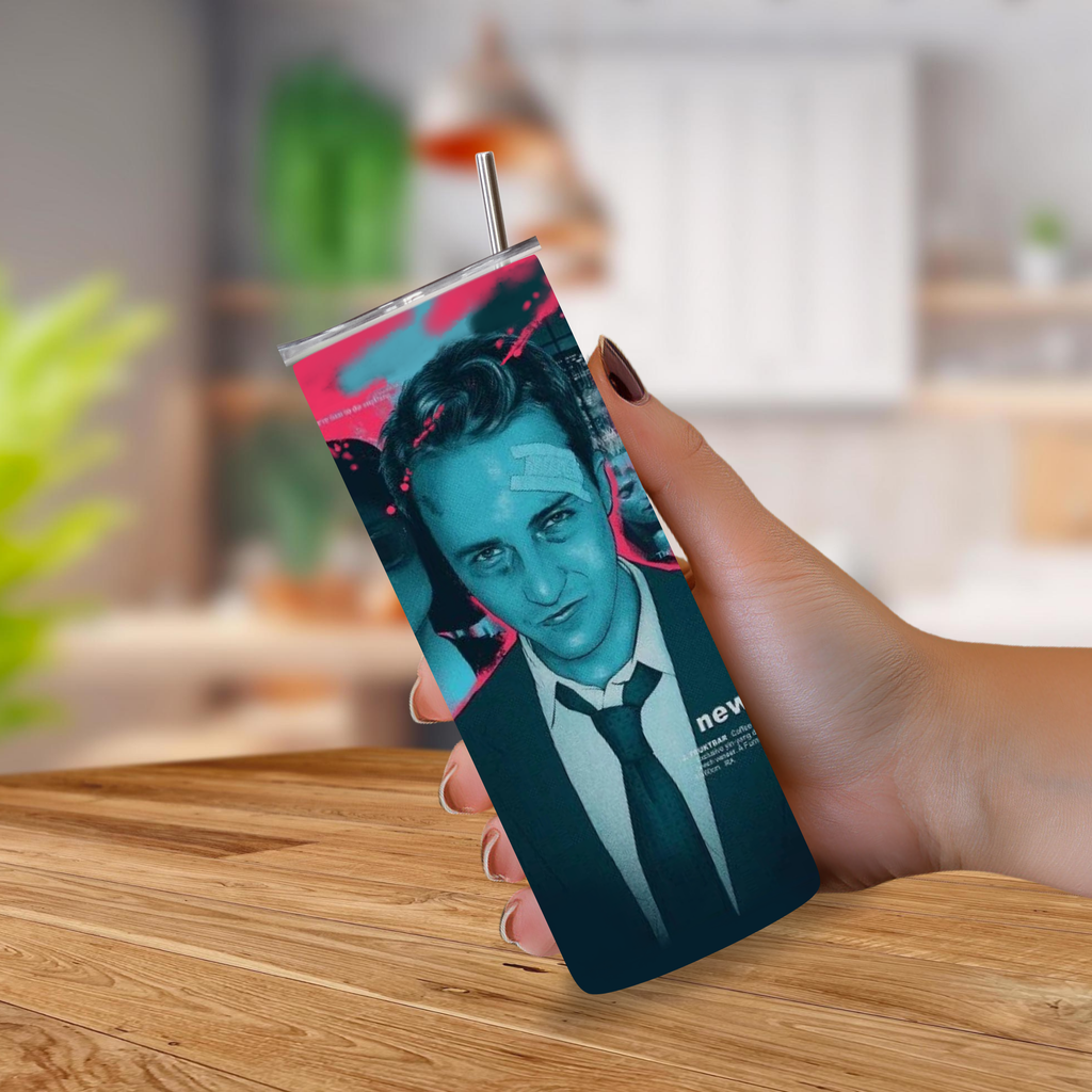 A hand holding a slim rectangular tumbler with a metal straw, featuring a stylized portrait of a man in a suit with teal, black, and pink graphic accents from the movie Fight Club, set against a blurred indoor background.