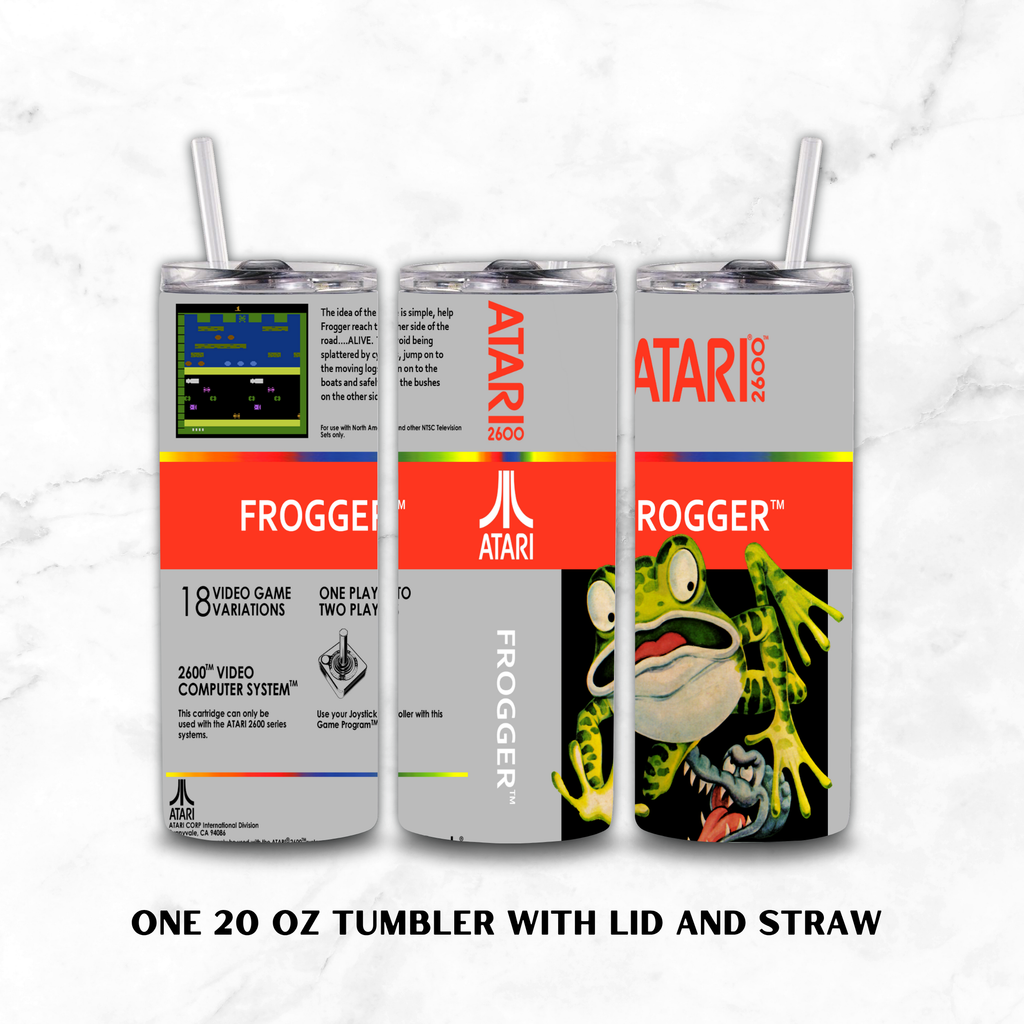 Three views of a 20 oz insulated tumbler with lid and straw, featuring retro Atari 2600 'Frogger' artwork on a light gray background. The tumbler wraps around the design with gray, red, black, and neon green elements, and text at the bottom reads 'ONE 20 OZ TUMBLER WITH LID AND STRAW'.