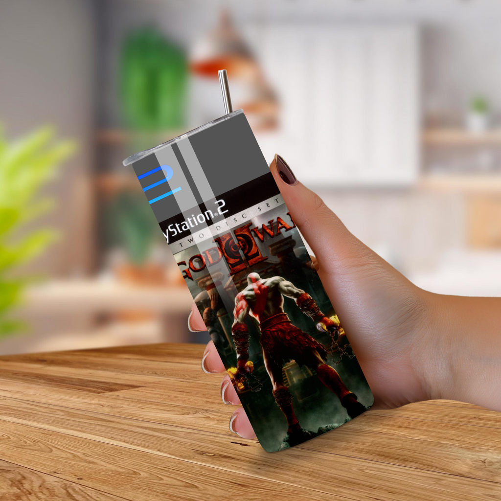 Person holding a 20oz tumbler with a gaming God Of War 2 design on a wooden surface 