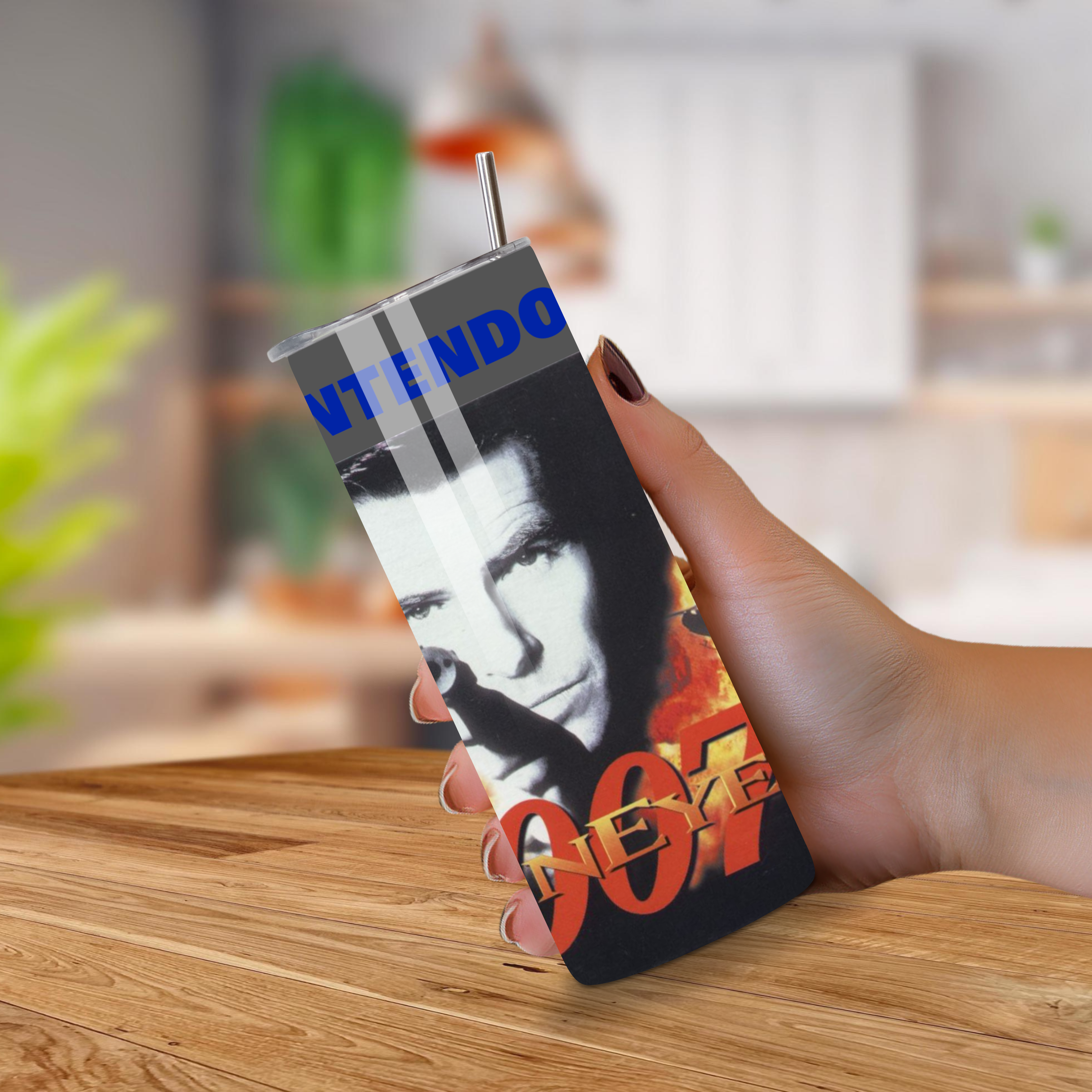 Person holding a Golden Eye 007-themed tumbler on a wooden surface with a blurred background