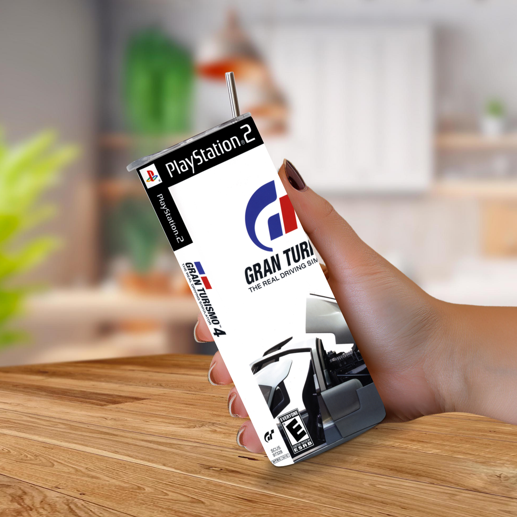 A hand holding a 20oz tumbler designed to look like a vintage PlayStation 2 game case for Gran Turismo 4, set against a blurred indoor background.