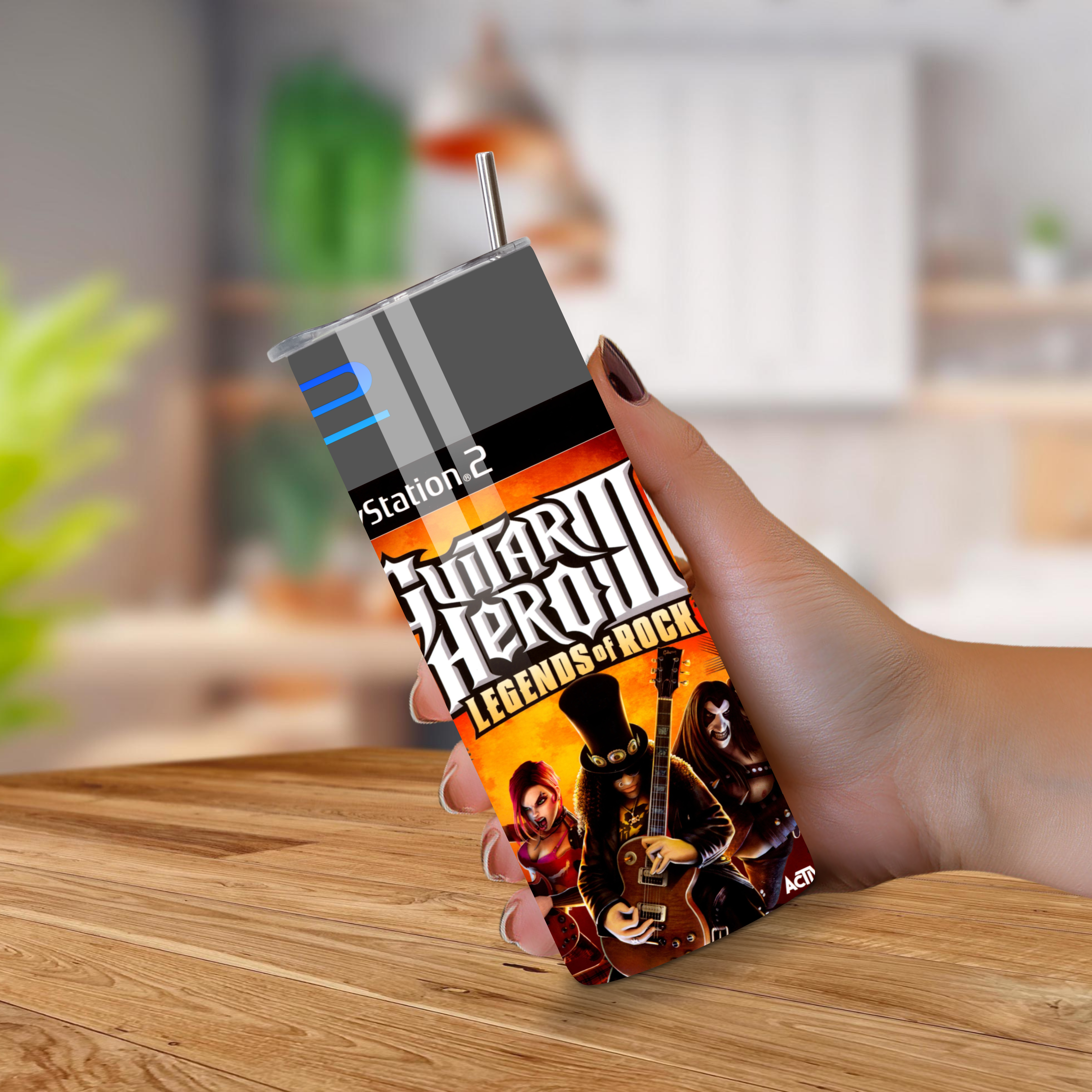 20oz tumbler with ' guitar hero' design held by a hand on a wooden surface