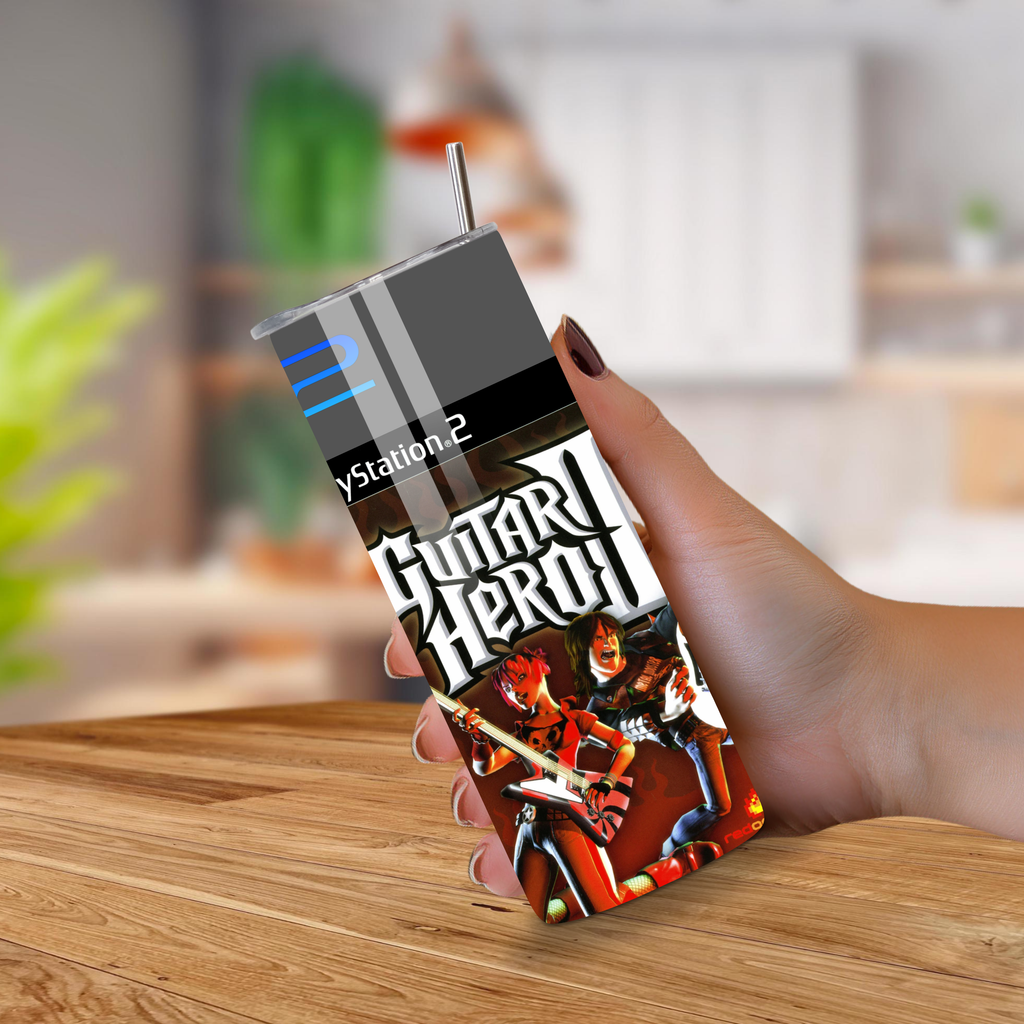 Hand holding a PlayStation 2 Guitar Hero II 20oz tumbler on a wooden surface with a blurred background