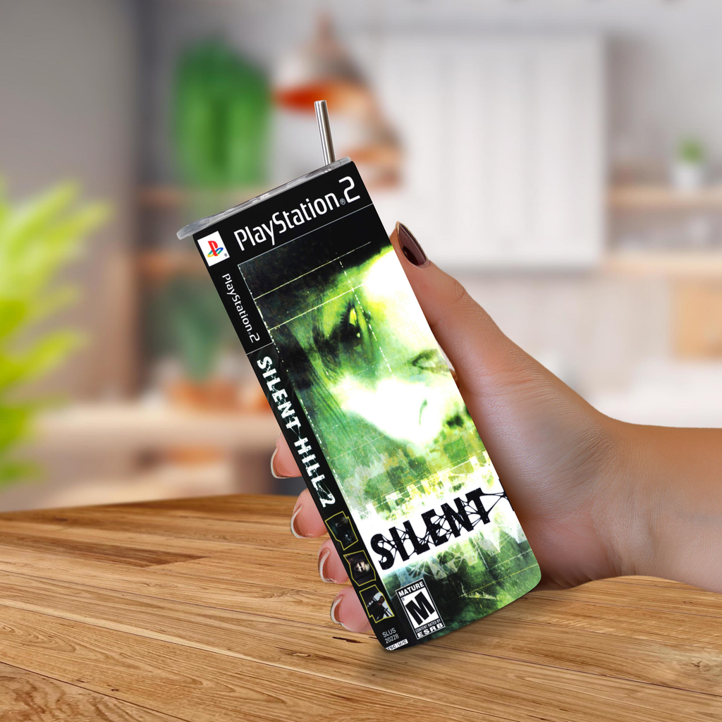 A hand holding a PlayStation 2 Silent Hill 2 game cover designed on a 20oz stainless steel tumbler , with a metal straw extending from the top, set against a blurred kitchen background.