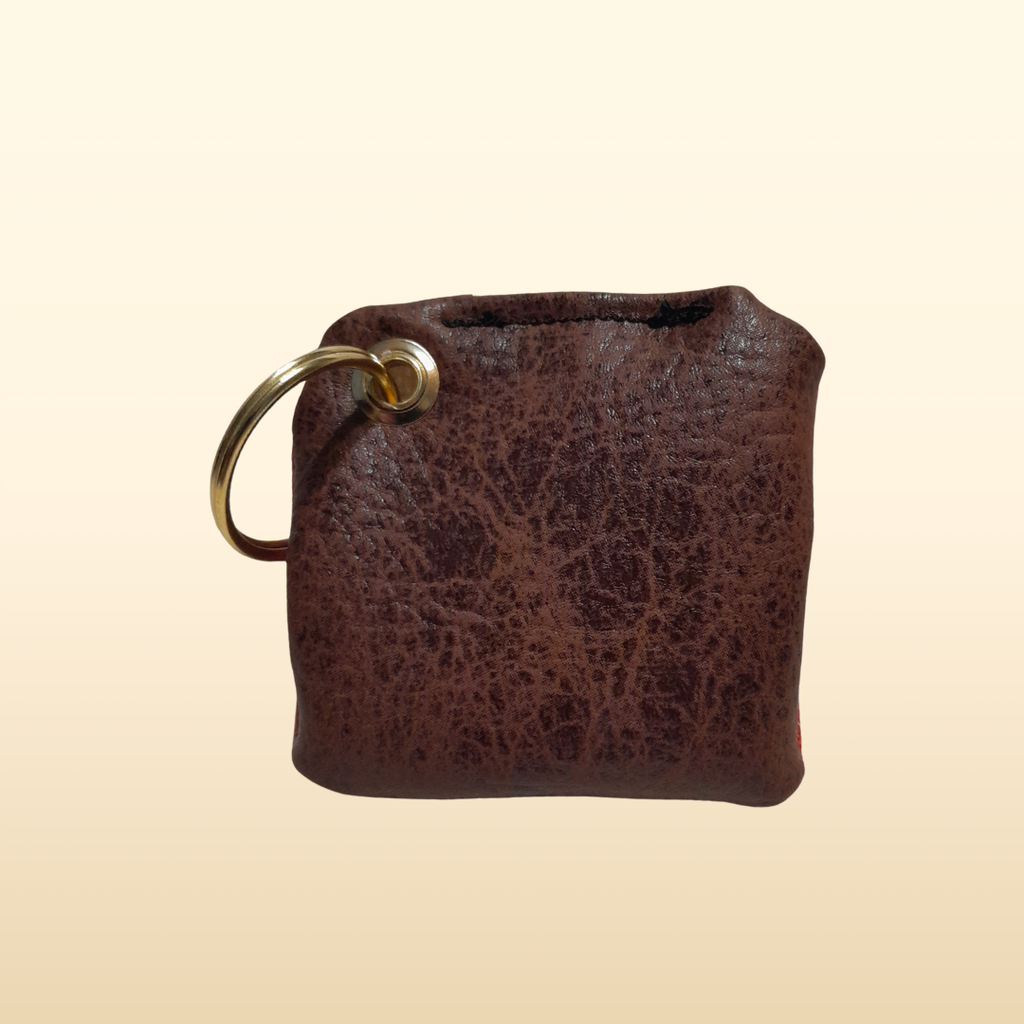 Brown leather keychain with gold ring on a beige background