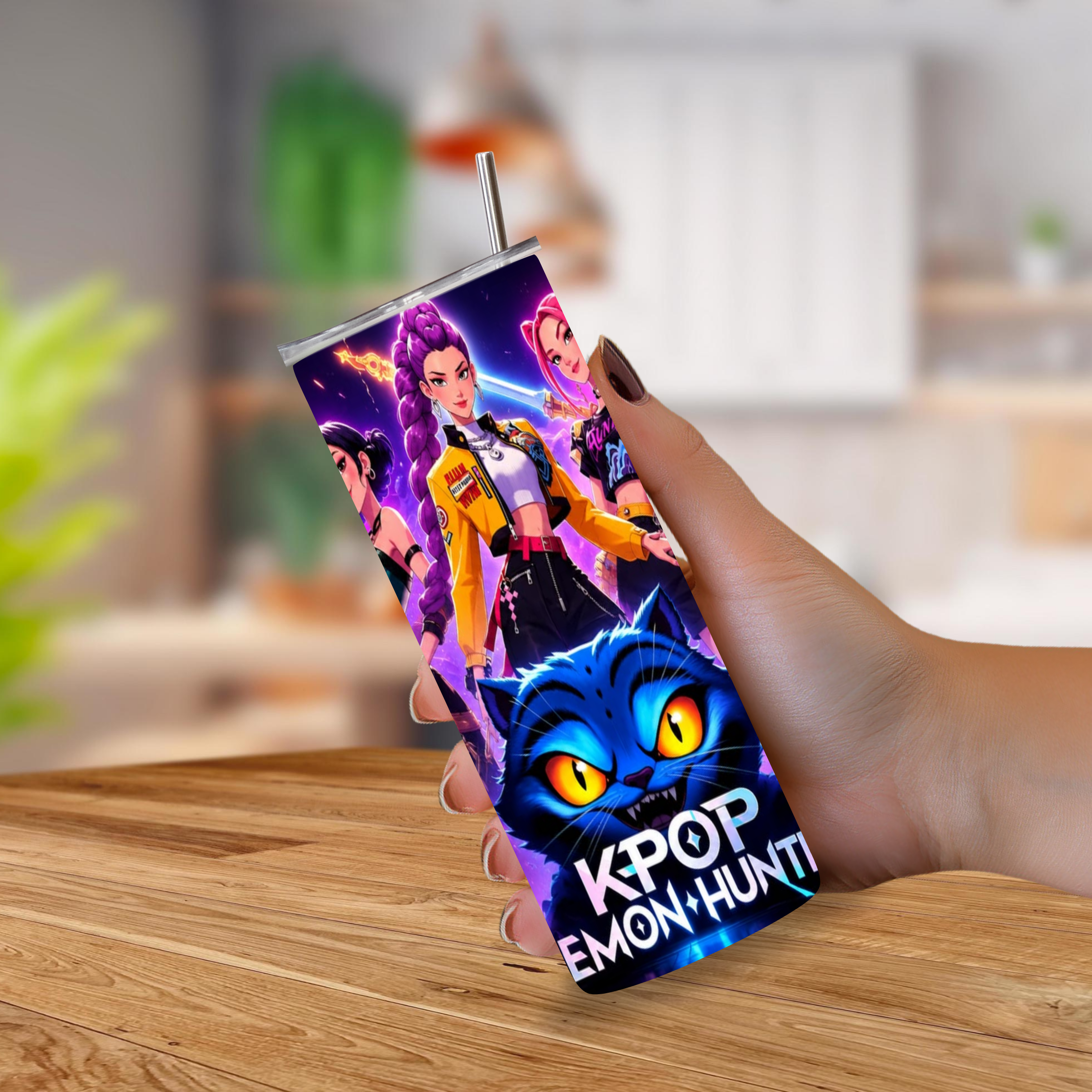 A hand holding a slim stainless-steel tumbler with a straw, featuring colorful cartoon characters and a large blue cat face with glowing yellow eyes. The text 'K-POP DEMON HUNTER' is printed on the tumbler.