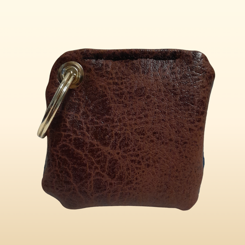 Brown leather keychain with a metal ring on a beige background