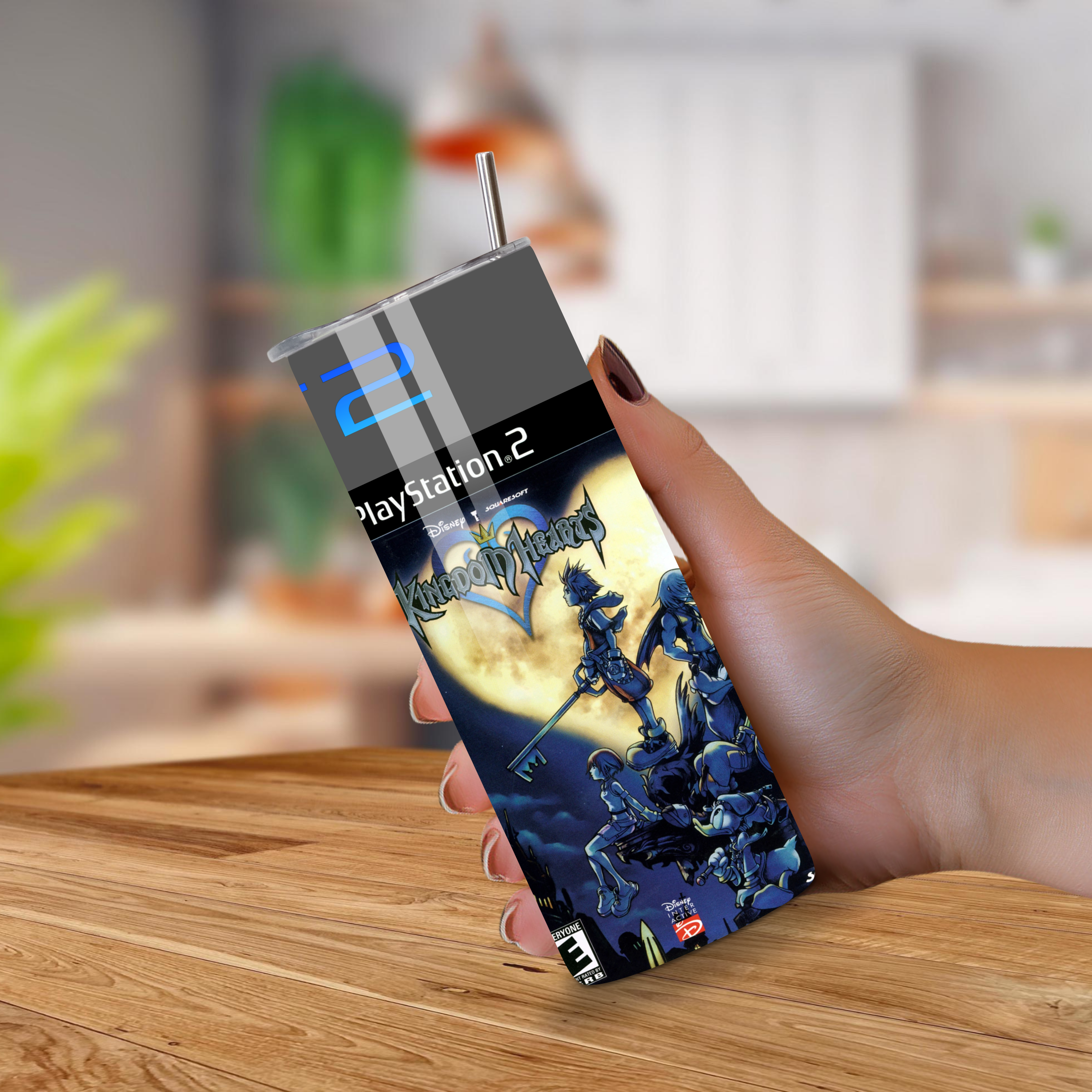 Hand holding a 20oz tumbler with Kingdom Hearts design on a wooden surface.