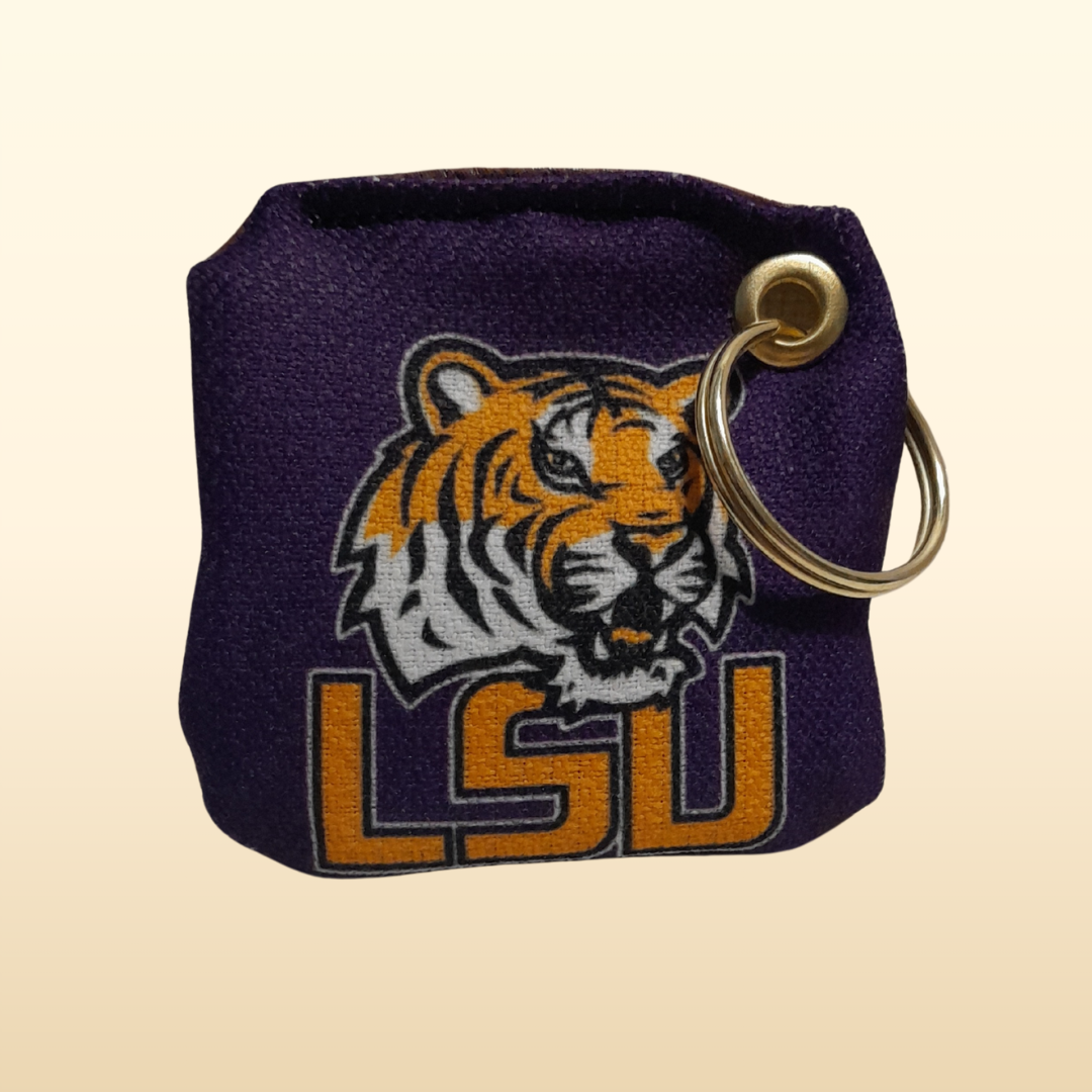 Purple keychain pouch with LSU tiger logo on a beige background