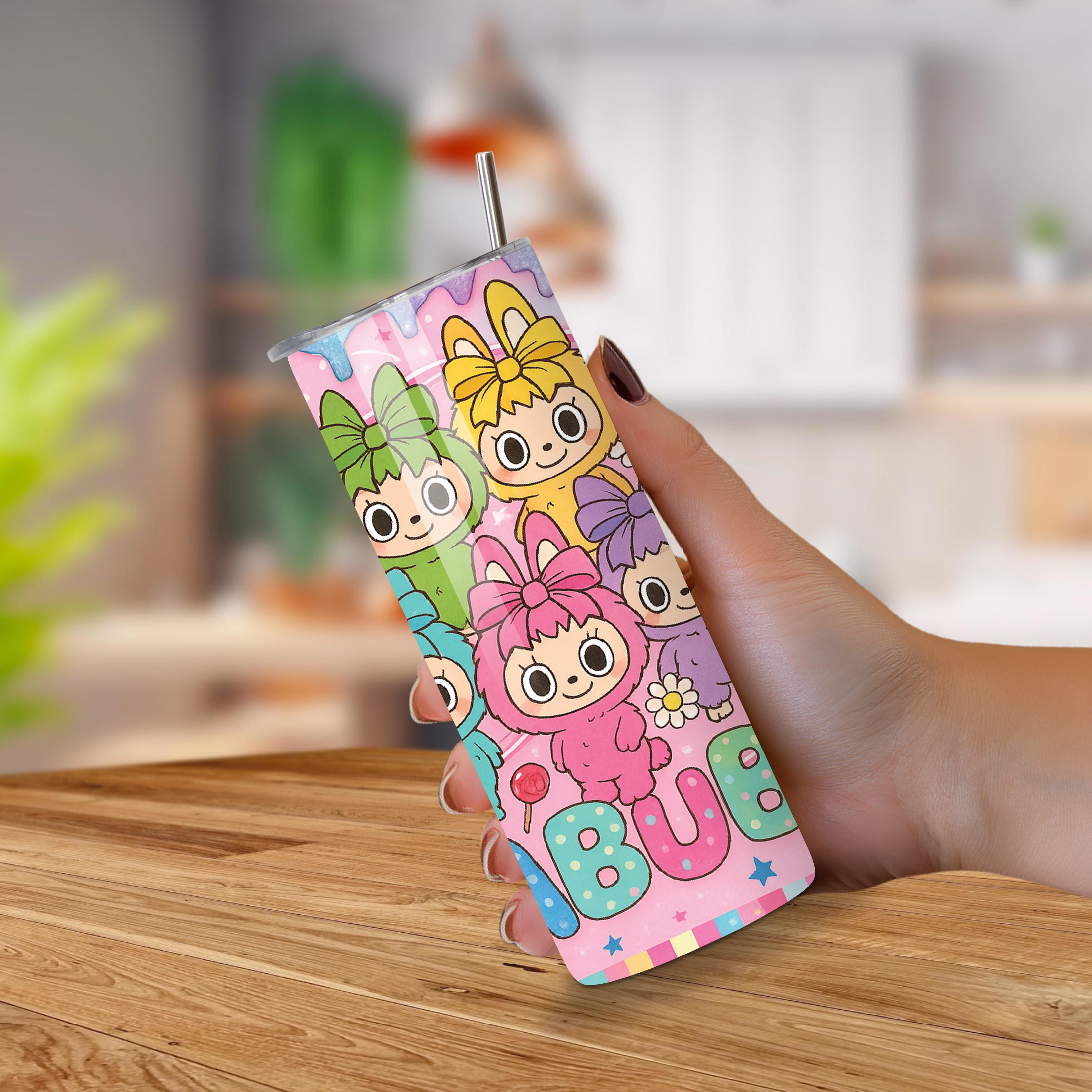 Colorful Tumbler with cartoon characters held by a hand on a wooden surface.