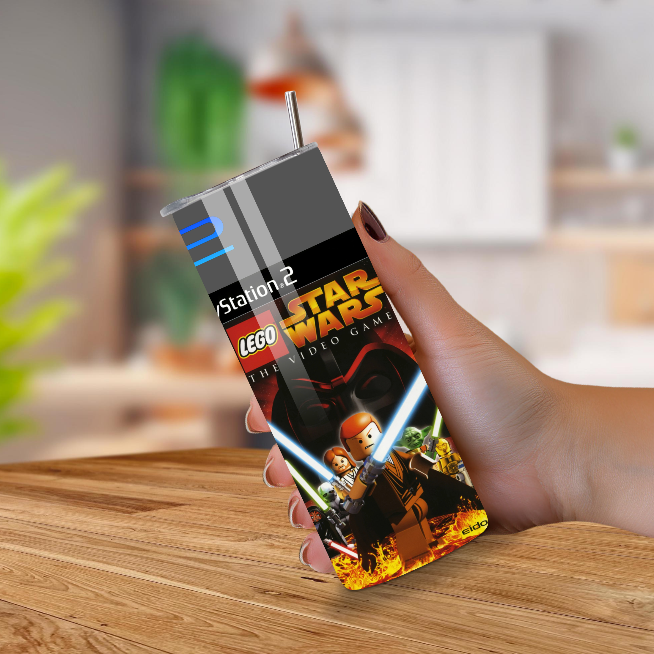 Hand holding a 20oz tumbler with a LEGO Star Wars design on a wooden surface.