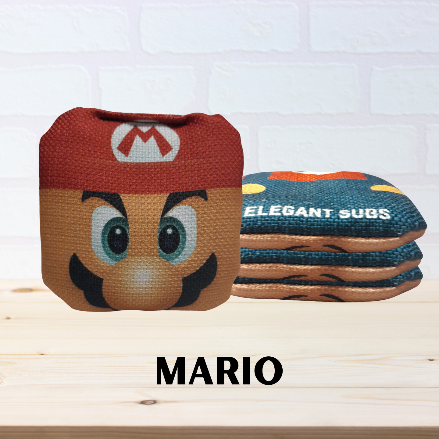 Mario-themed mini cornhole bags labeled 'Elegant Subs' on a light wooden surface.