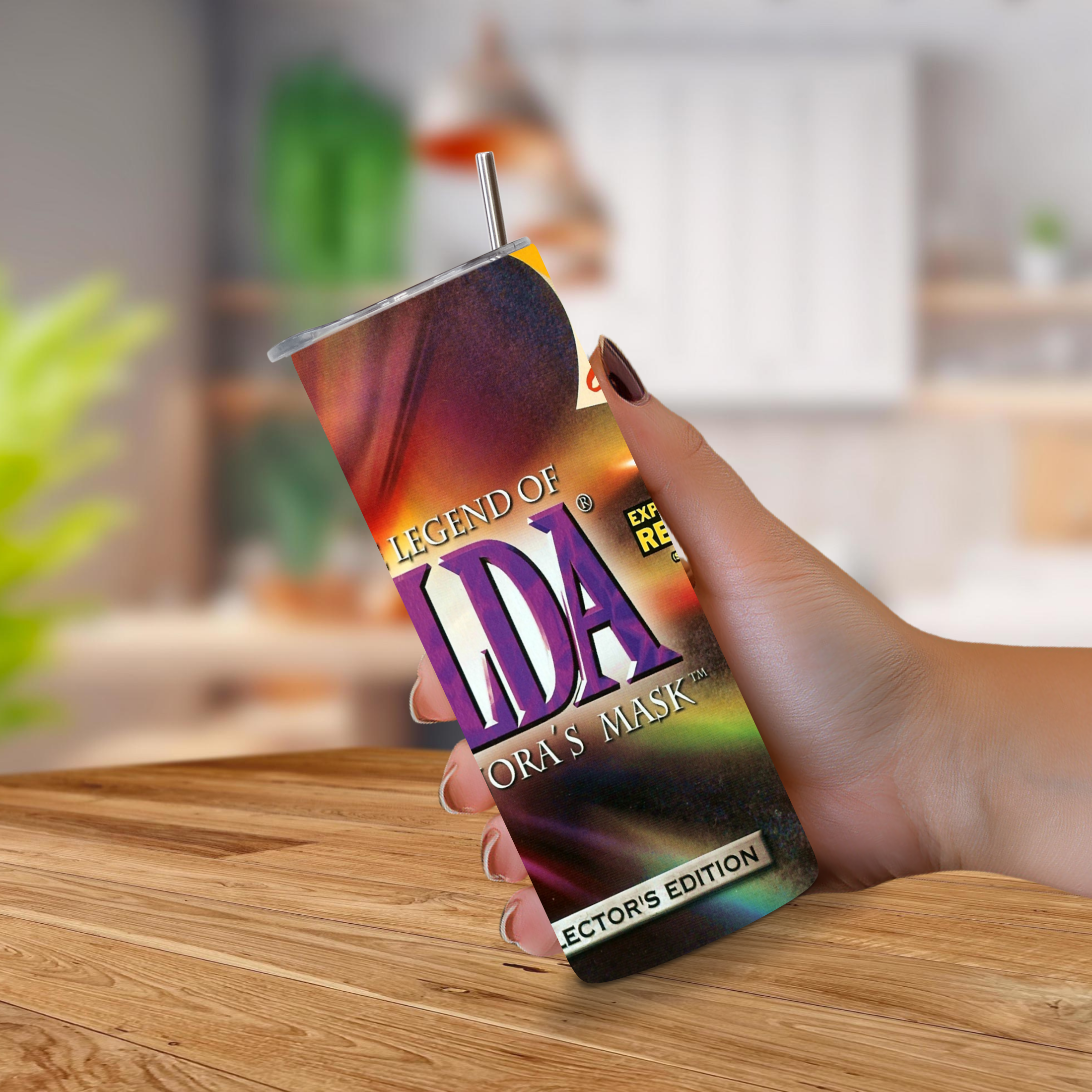 A hand holding a 20oz stainless steel tumbler with a straw. The cup has a glossy, iridescent cover featuring the text 'LEGEND OF ZELDA MAJORA'S MASK' in purple and white, with a colorful rainbow gradient background.