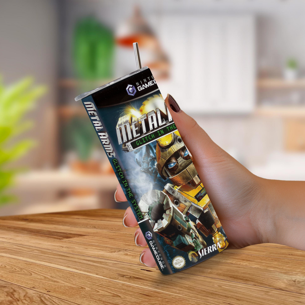 A hand holding a novelty 20oz stainless steel tumbler designed to look like a GameCube game cover featuring Metal Arms Glitch in the System artwork, with a metal straw inserted at the top.