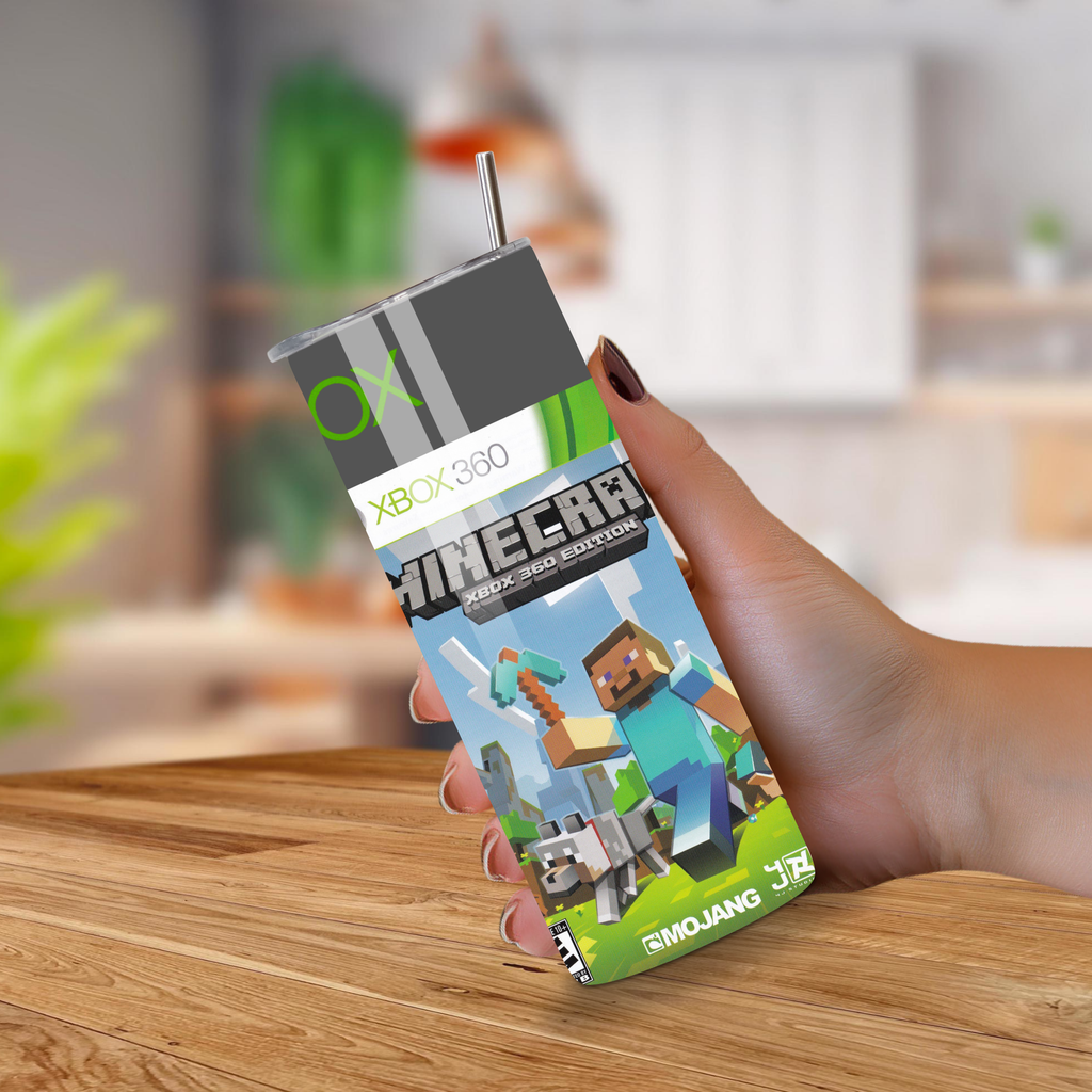 Hand holding a Minecraft Xbox 360 edition tumbler on a wooden surface with a blurred indoor background.