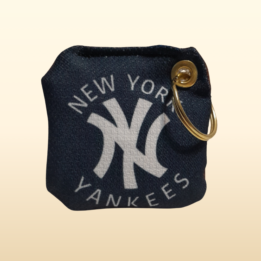 Navy blue keychain pouch with New York Yankees logo and gold ring on beige background