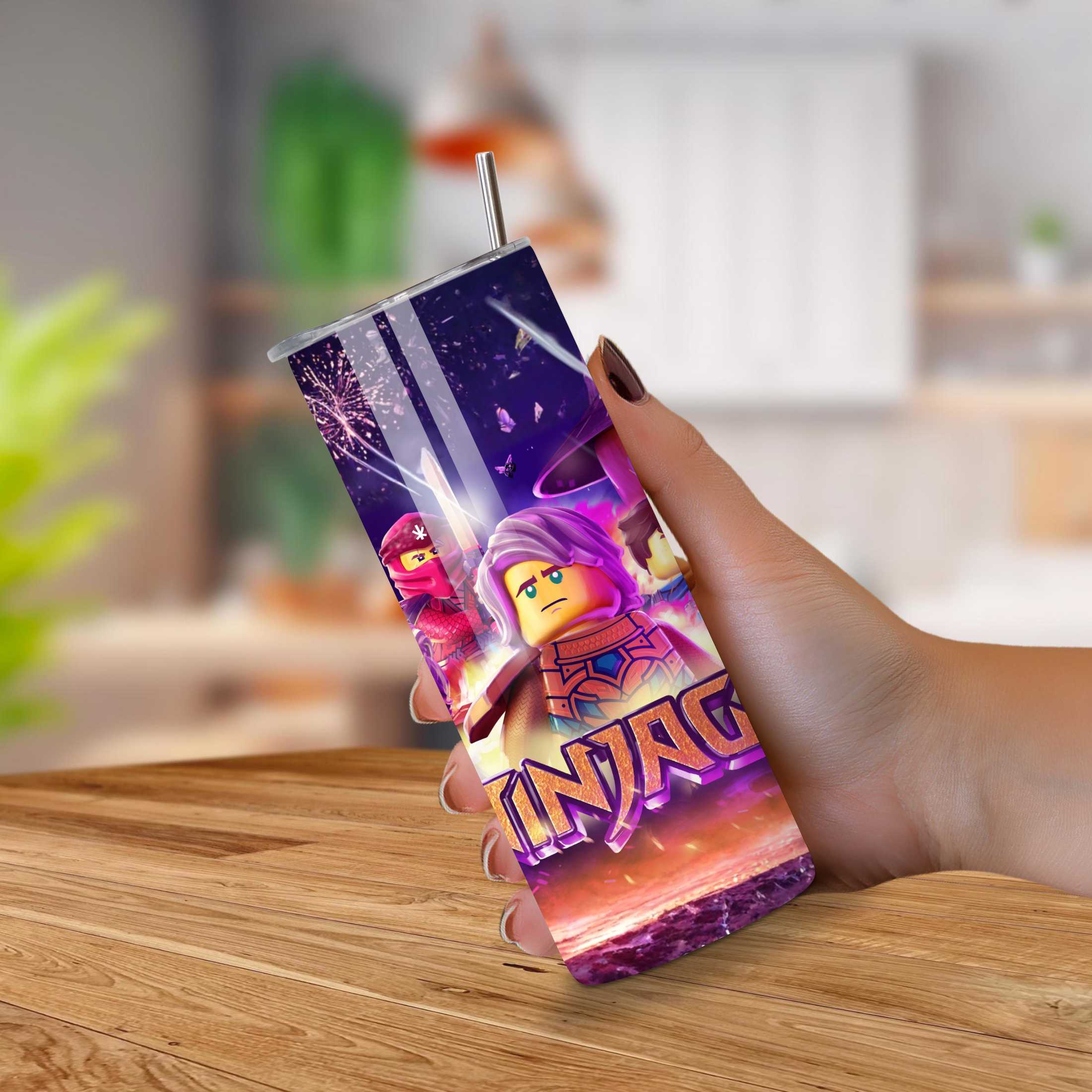 Person holding a 20oz tumbler with a colorful design featuring characters and the word 'Ninjago' on a wooden surface.