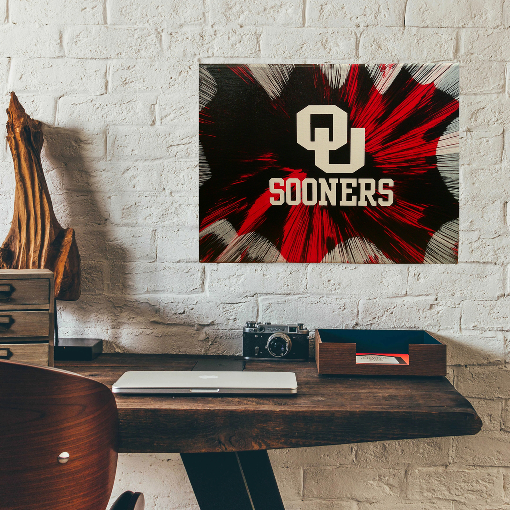 Desk with an Oklahoma Sooners Spin Art against a white brick wall