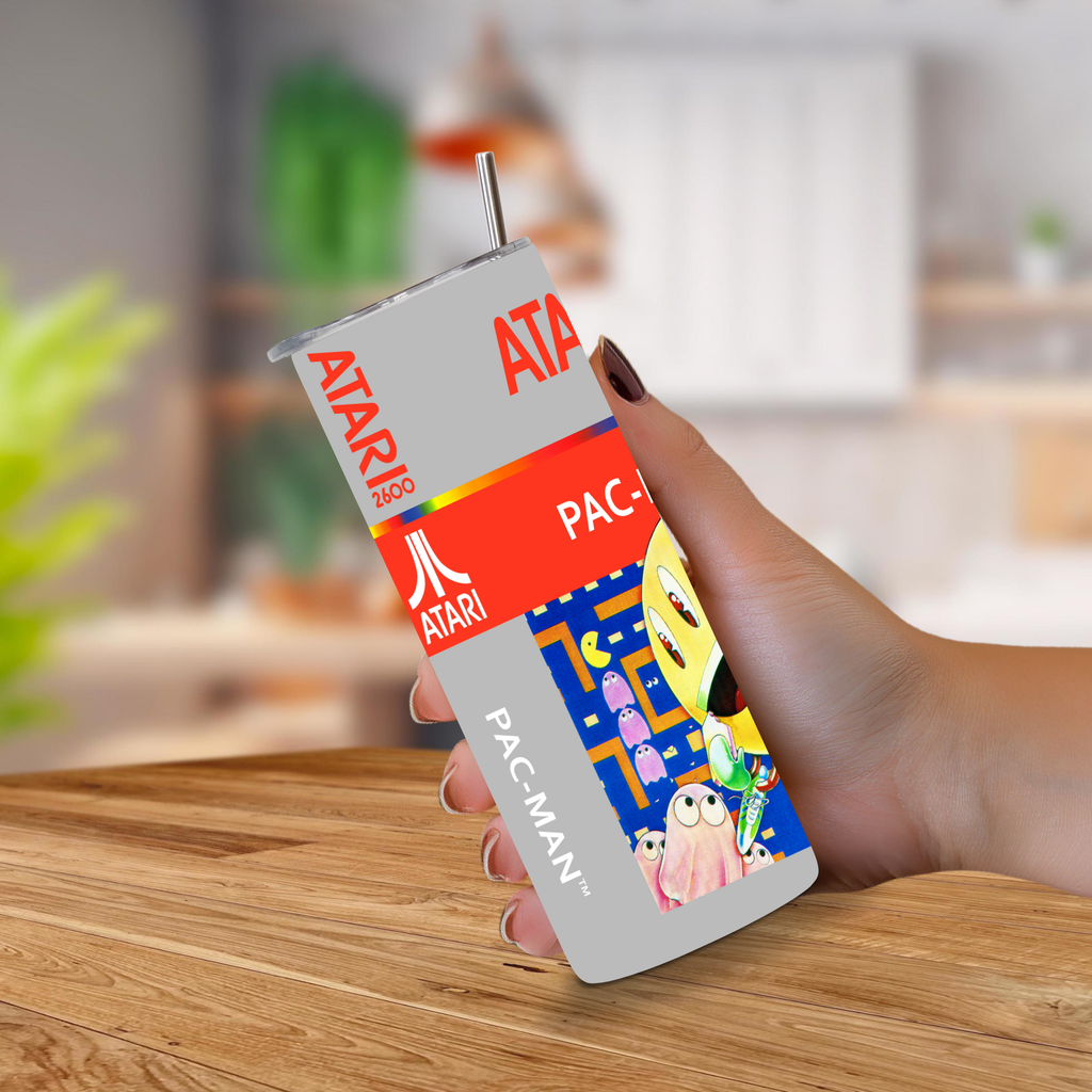 A hand holding 20oz stainless steel tumbler of atari 2600 Pac-Man theme on a blurred kitchen background 