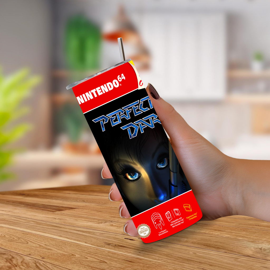 A hand holding a Nintendo 64 Perfect Dark 20oz tumbler with a straw, set against a blurred indoor background with a wooden table.