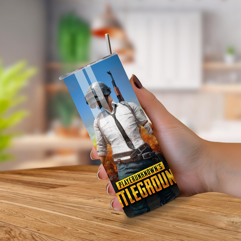 Tumbler with 'PlayerUnknown's Battlegrounds' design held by a hand on a wooden surface.