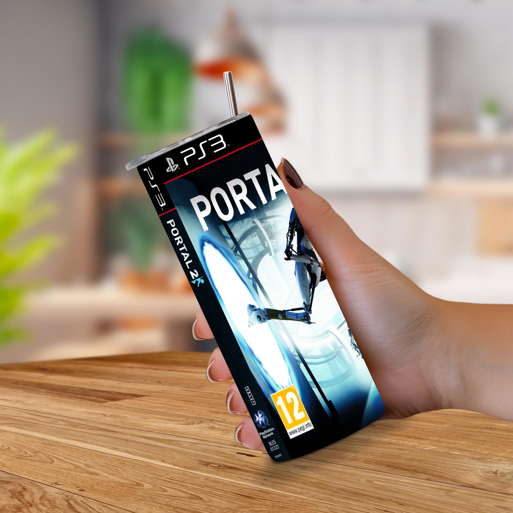 A hand holding a PlayStation 3 game cover styled to look like 20oz stainless steel tumbler for Portal 2, with a metal straw sticking out of the top, set against a blurred indoor background.