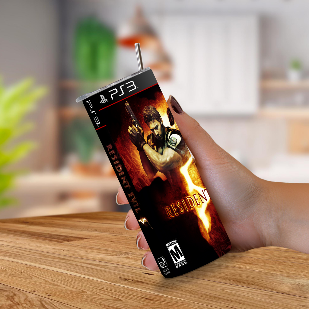 A hand holding a PS3-shaped 20oz stainless steel tumbler with a straw, printed with Resident Evil 5 artwork, set against a blurred indoor background.