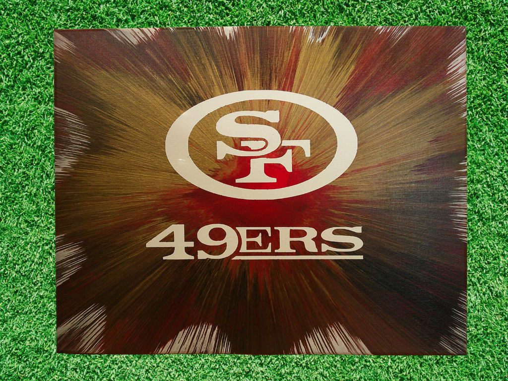 Spin Art of San Francisco 49ers logo with a radiant design on a green grass background