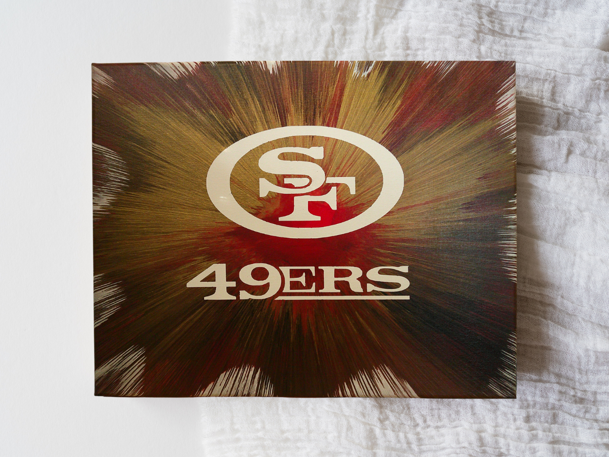 Spin art canvas of San Francisco 49ers logo with colorful radial team colors on a textured surface