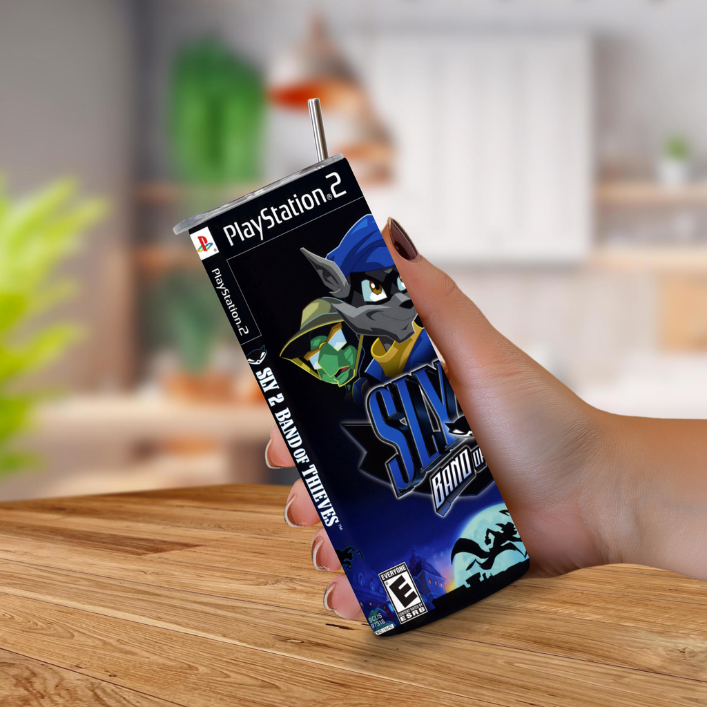 A hand holding a 20oz tumbler with PlayStation 2 Sly 2: Band of Thieves design set against a blurred kitchen background.