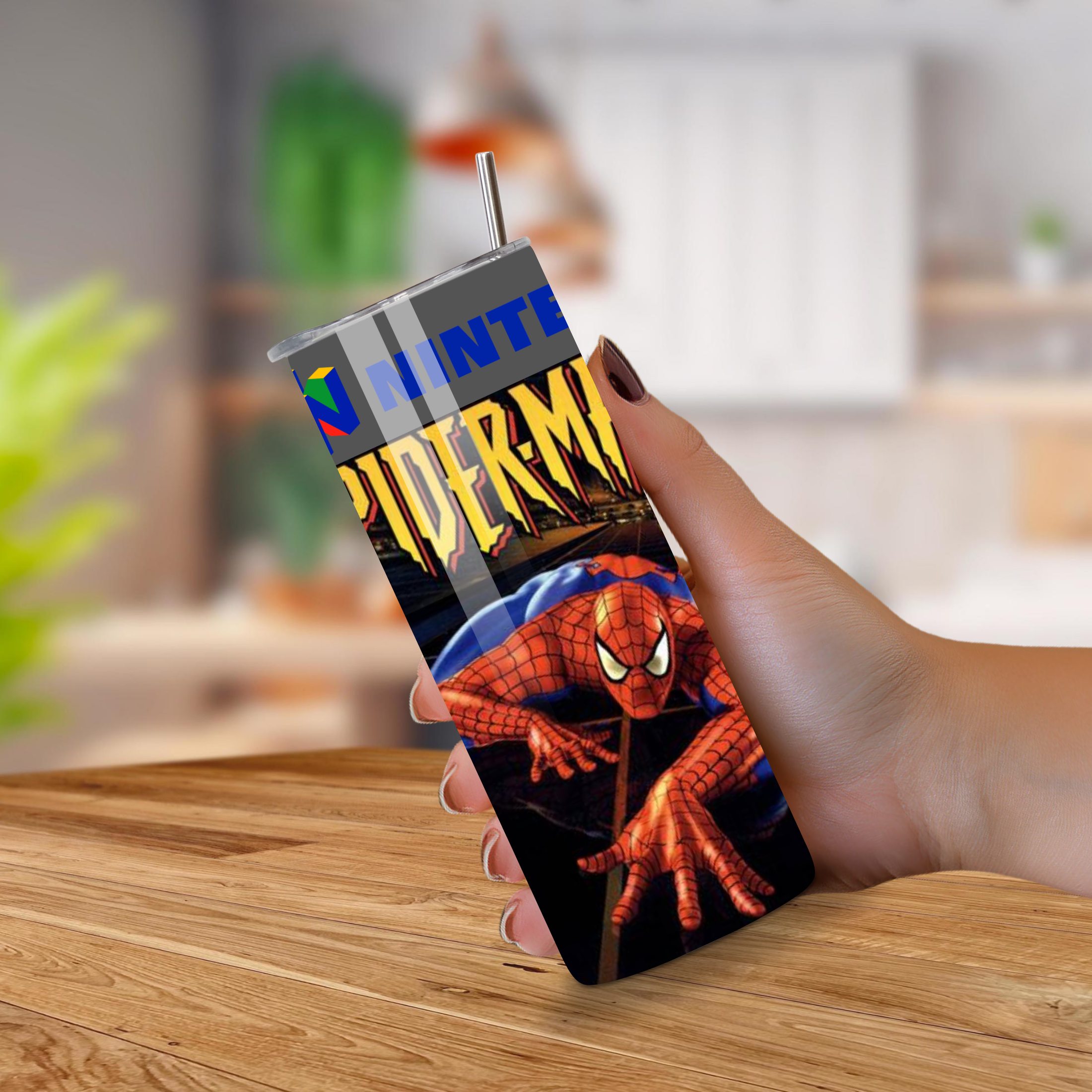 Person holding a with a tumbler with Spider-Man-themed on a wooden surface.