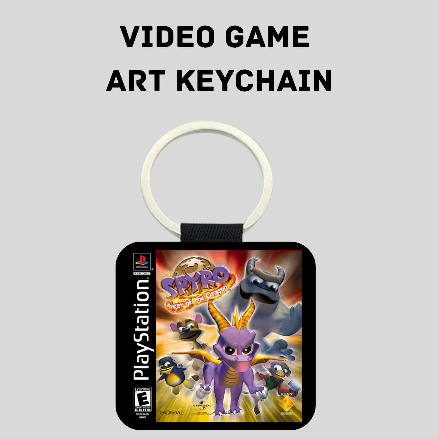 A PlayStation Spyro: Year of the Dragon Game art keychain shown on a light gray background with the text 'VIDEO GAME ART KEYCHAIN' above it. The keychain features a square black-bordered print with colorful Spyro artwork, a PlayStation logo on the left, and a white split ring.